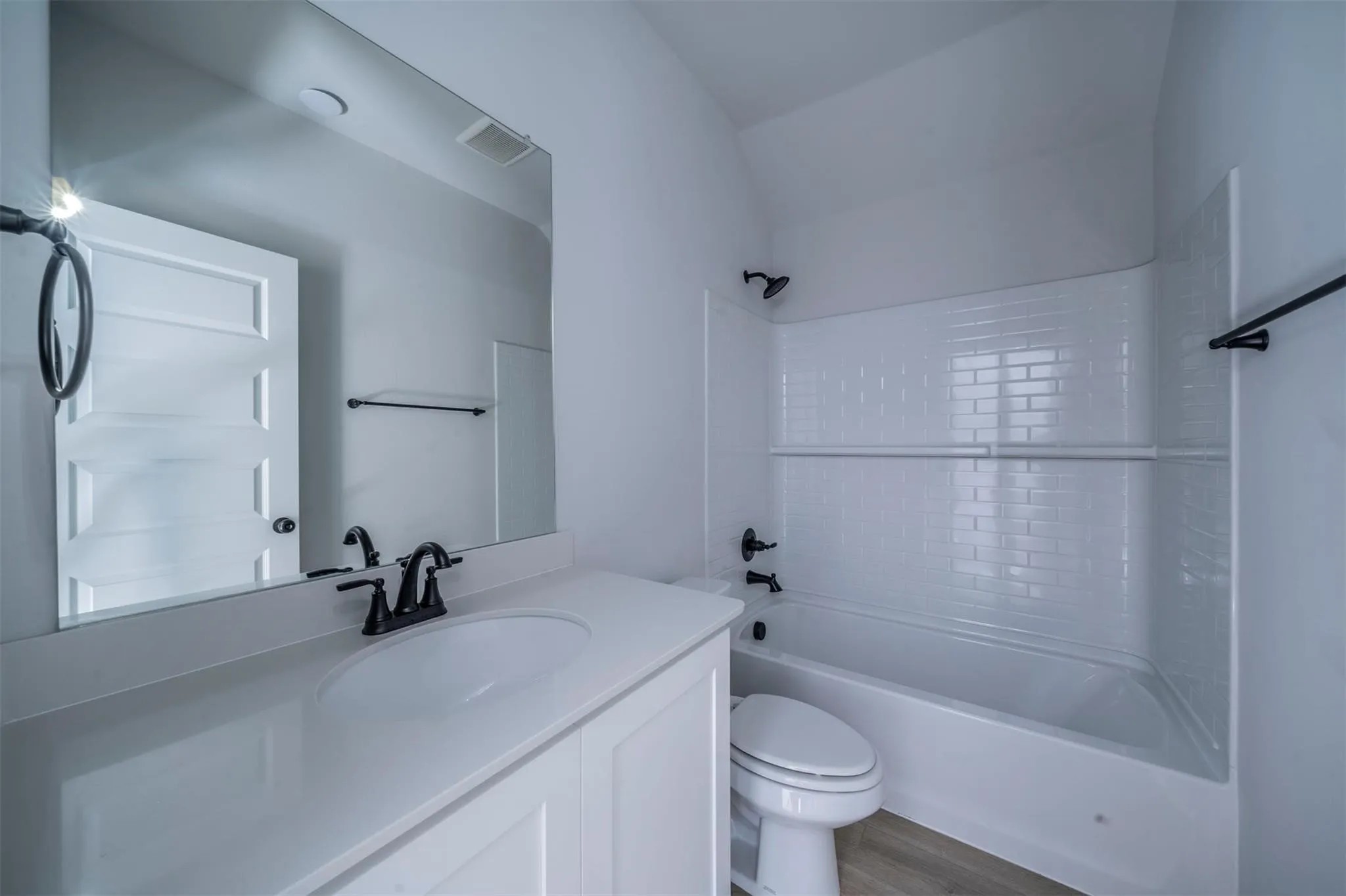 Bathroom featuring a white vanity with an integrated sink, matte black faucet, and a large mirror