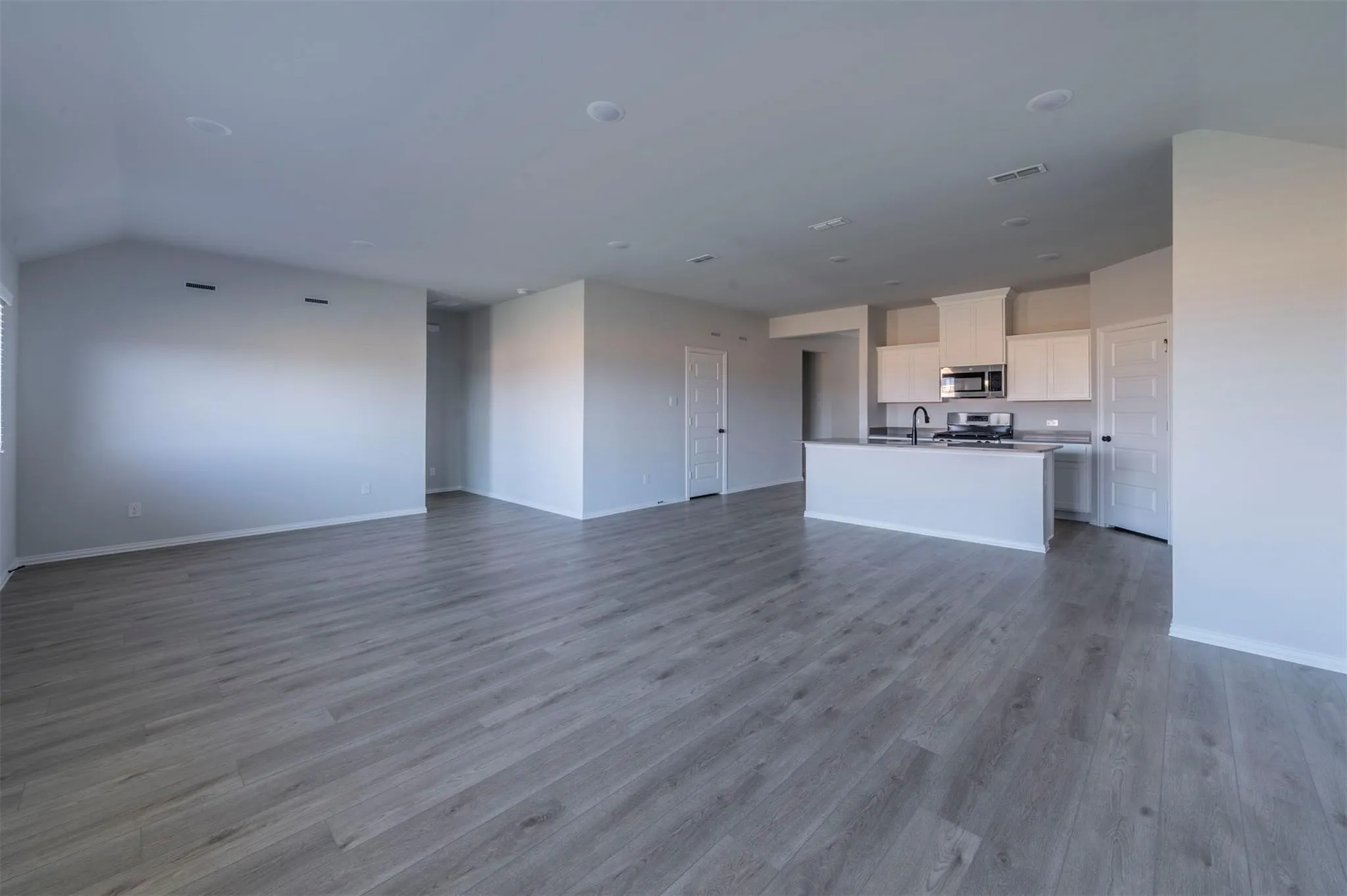 Spacious interior featuring wood-finish flooring, recessed lighting, and an open-concept kitchen