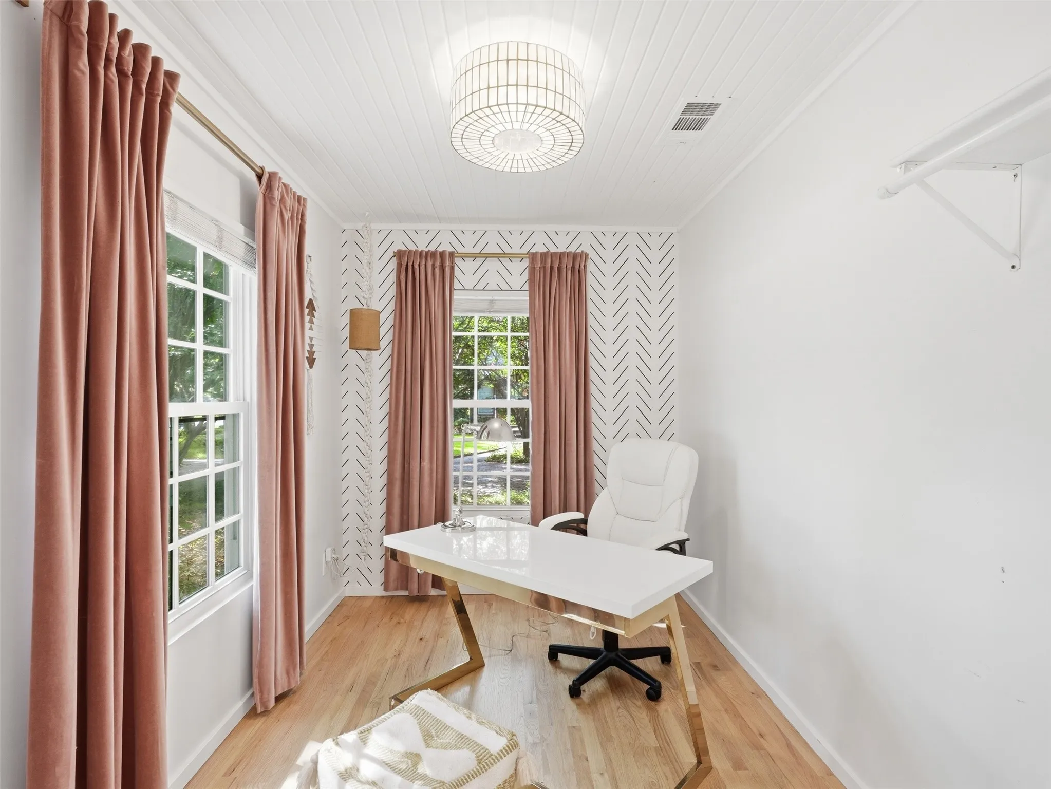 Bright room featuring wood-finish flooring, two large windows, a white shiplap ceiling, and a central decorative lighting fixture