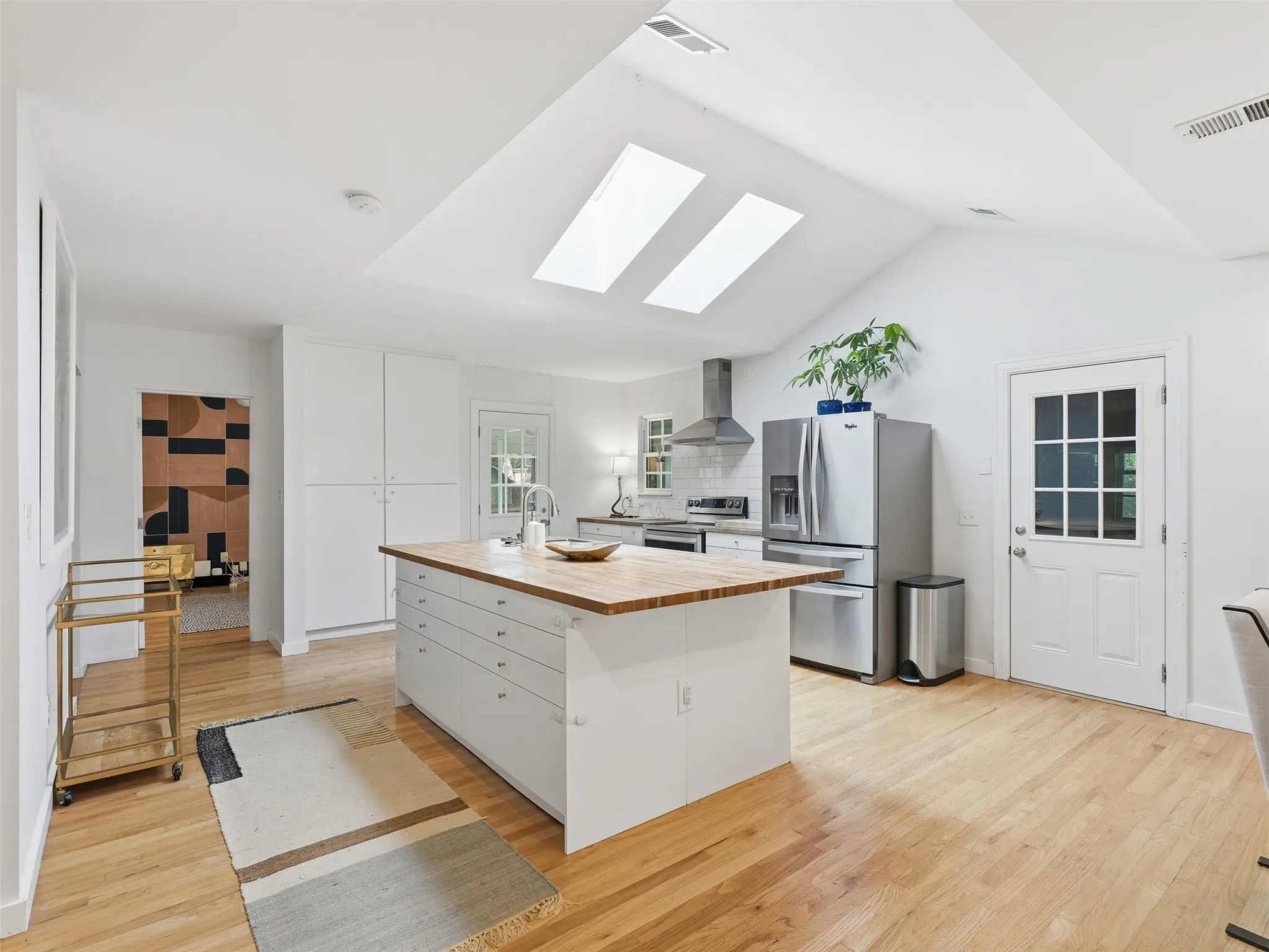 Vaulted ceilings with two skylights illuminate the open-concept kitchen, featuring light wood-finish flooring
