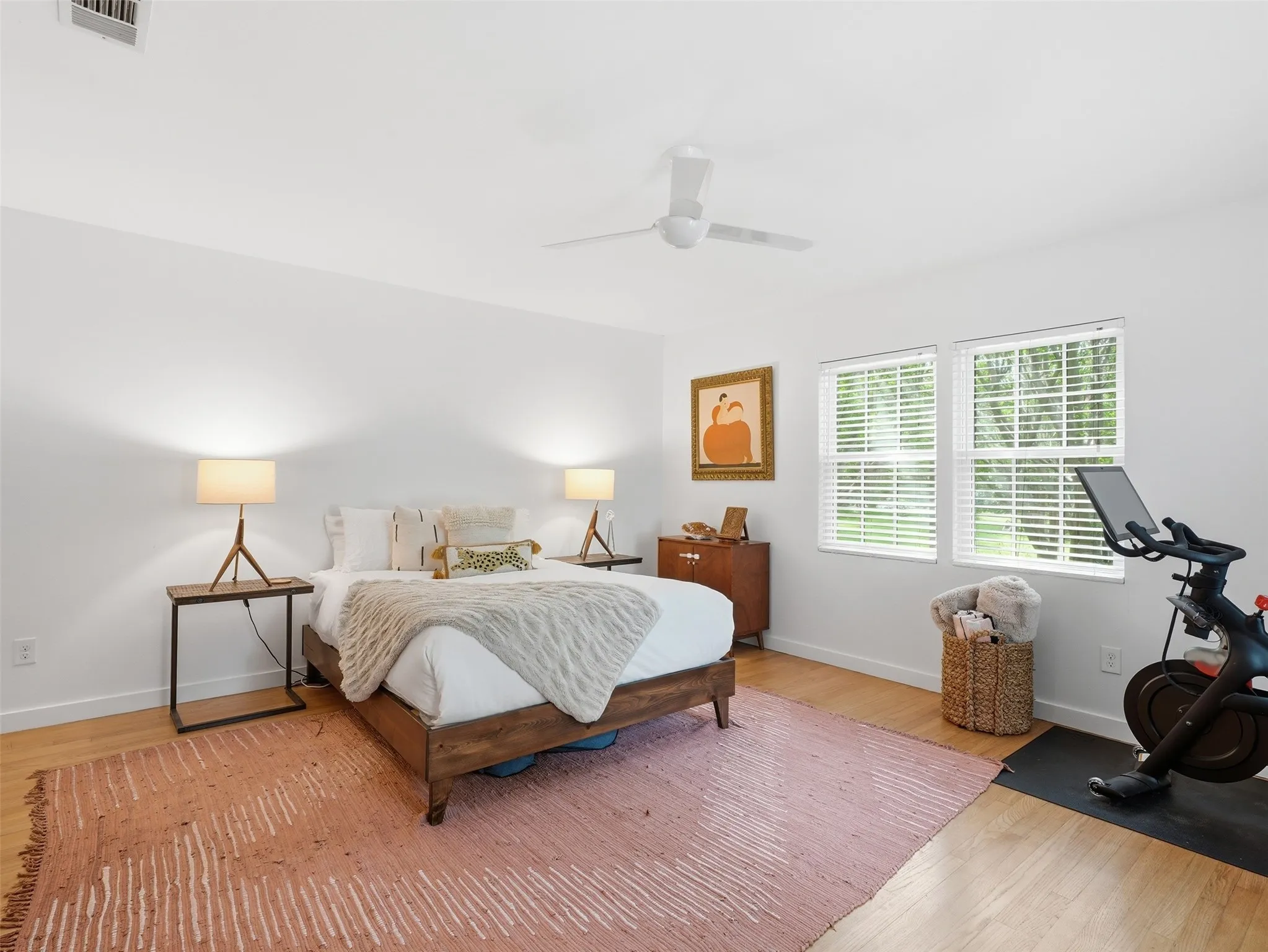 Bright interior room featuring wood-finish flooring, white walls, and a ceiling fan