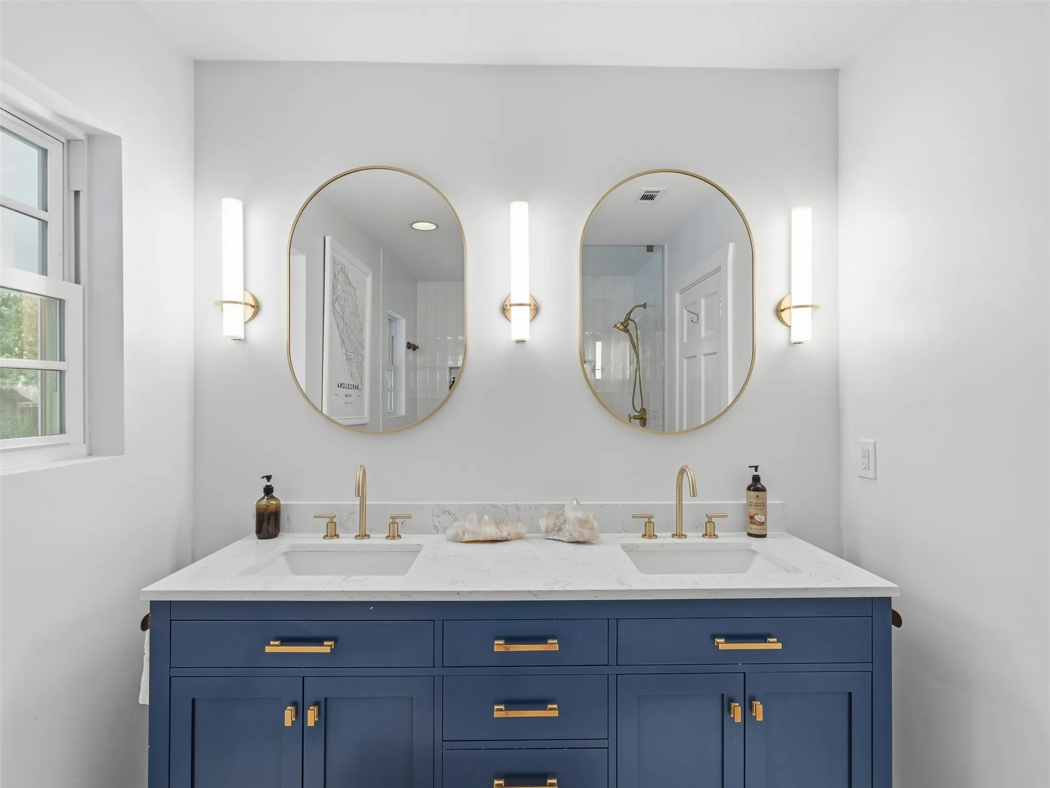 Dual vanity with a deep blue base cabinetry and gold-tone hardware