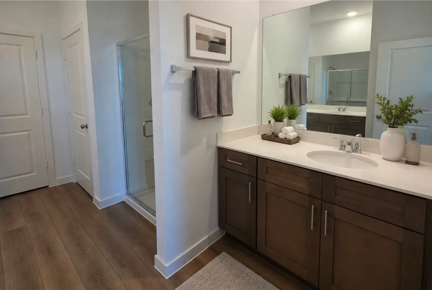 Spacious bathroom featuring an expansive single vanity with wood-finish cabinetry, light-toned countertop, and an integrated basin