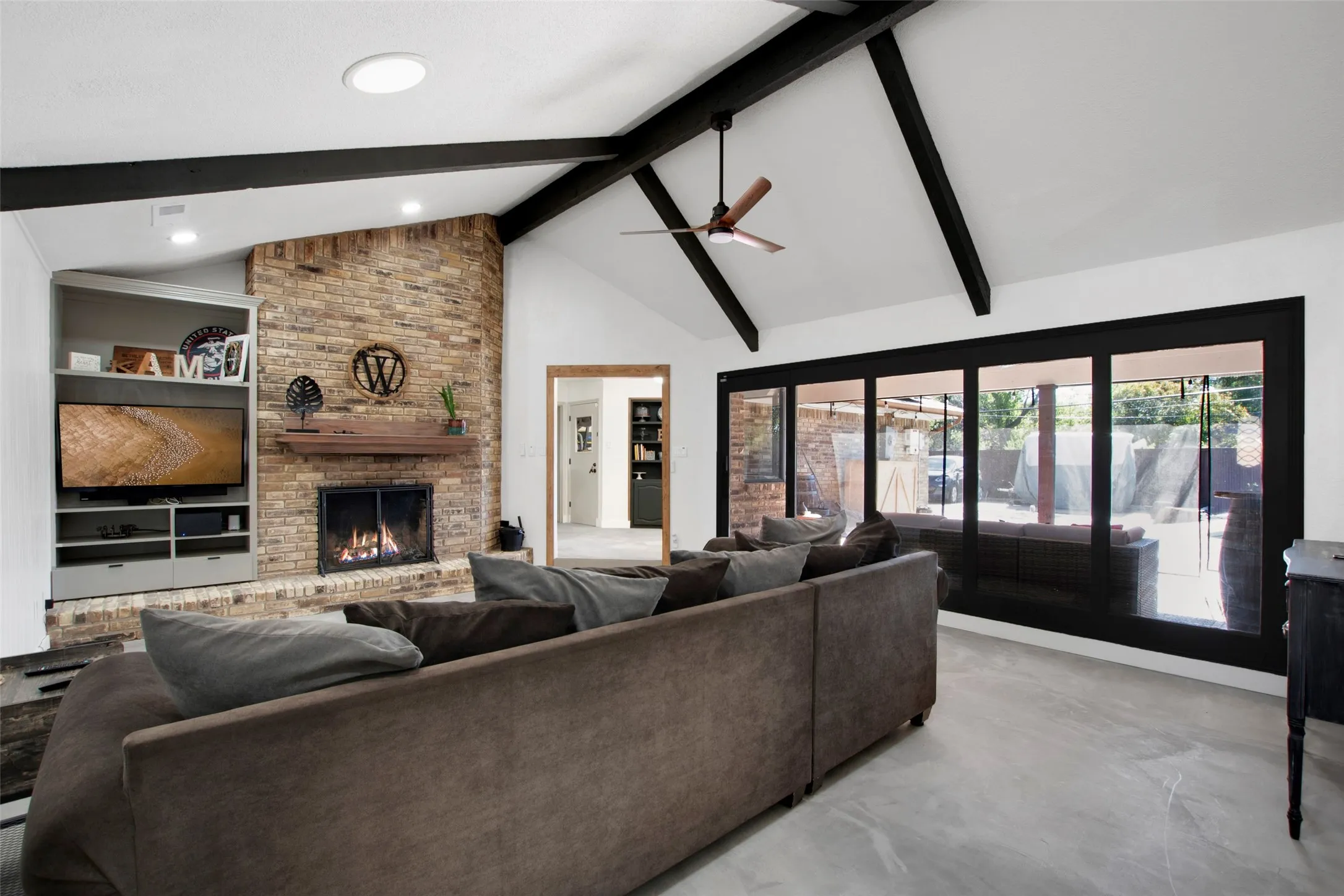 Living room featuring high vaulted ceiling, a fireplace, a healthy amount of sunlight, and beam ceiling