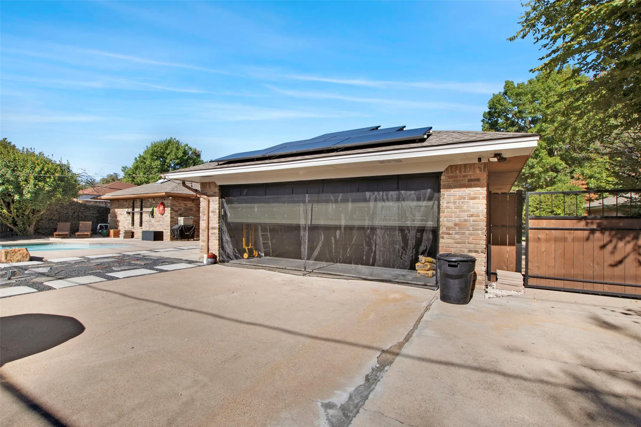 Garage with solar panels and a fenced in pool
