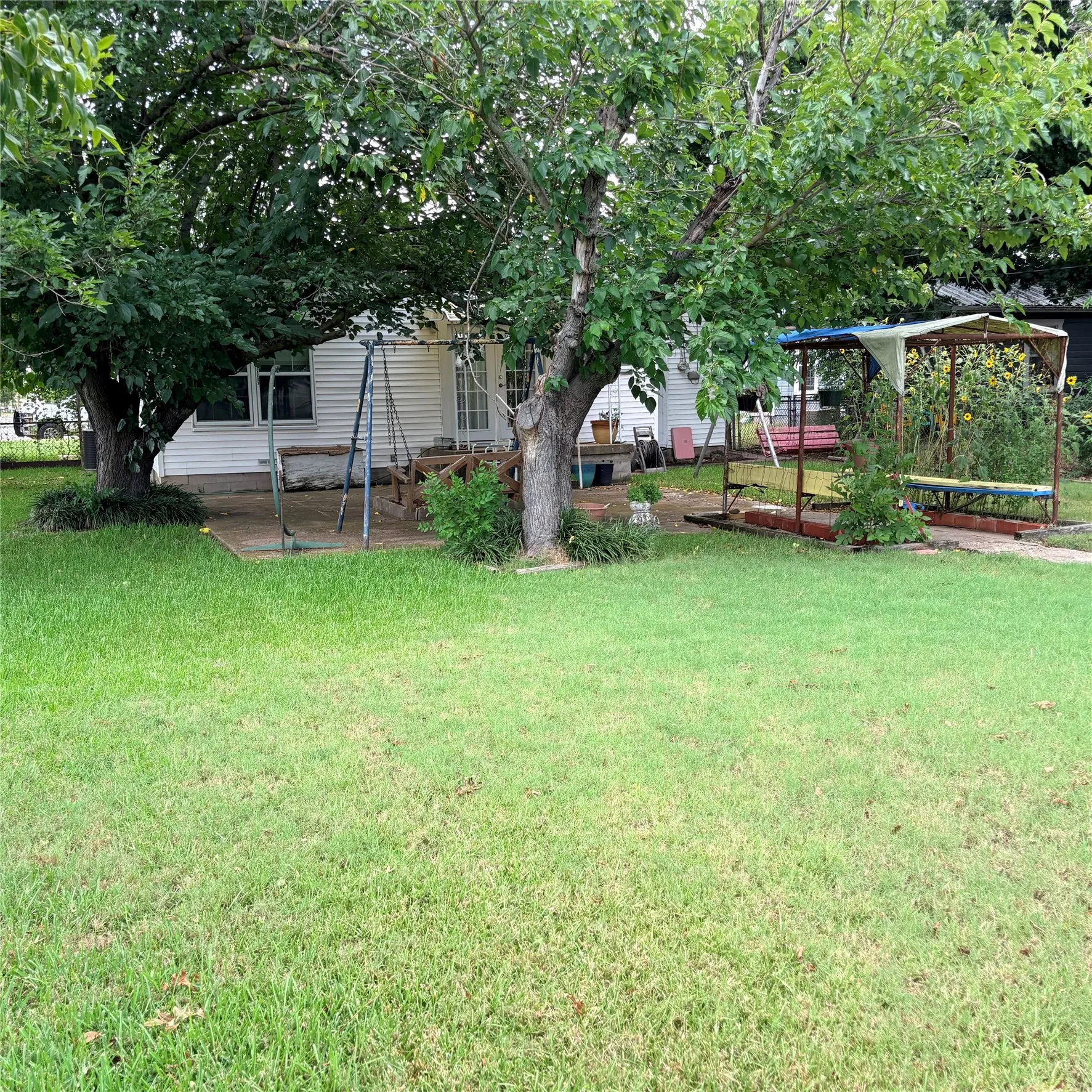 Expansive lawn area with mature trees and a concrete patio