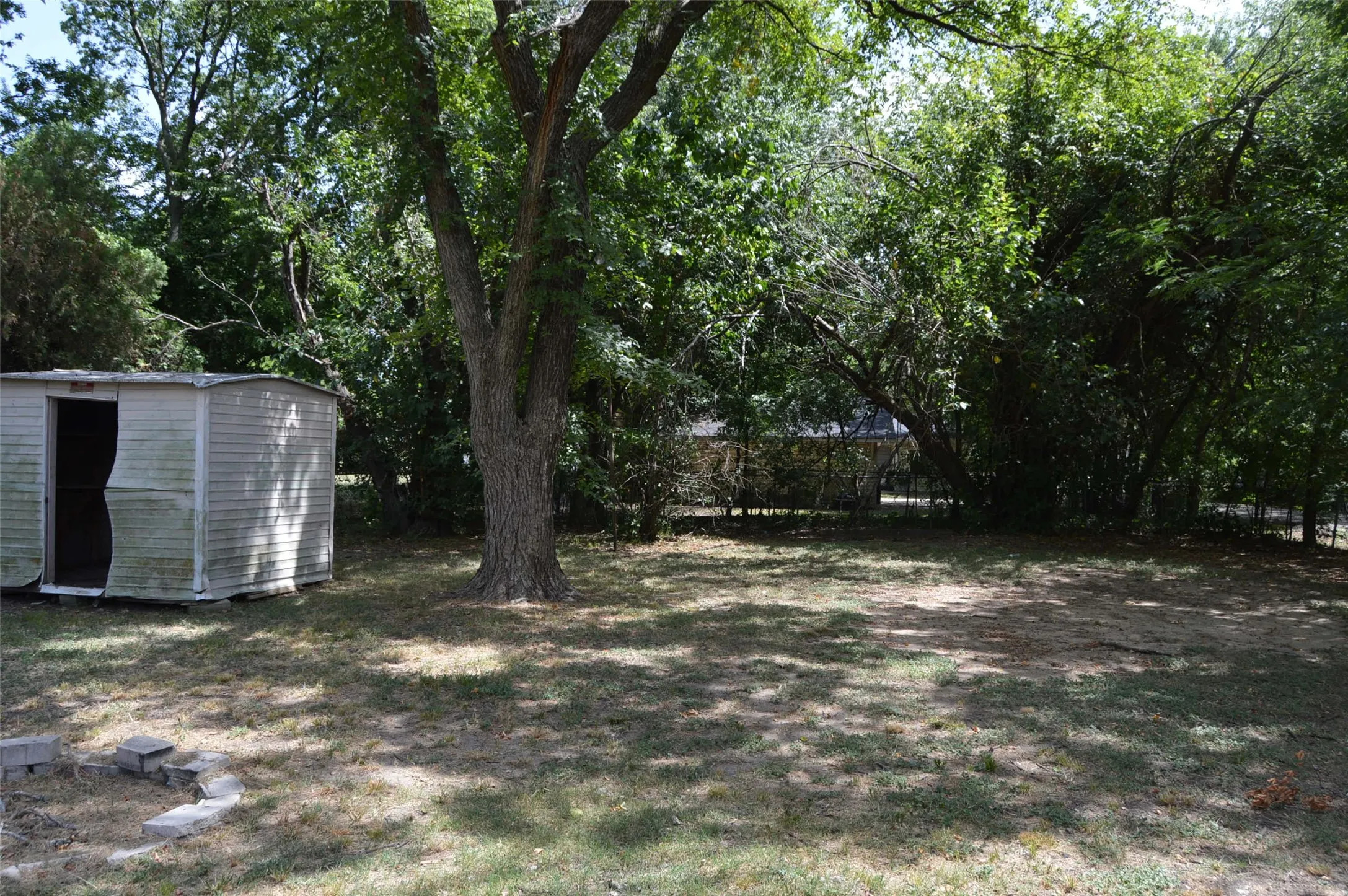 View of fenced backyard and storage