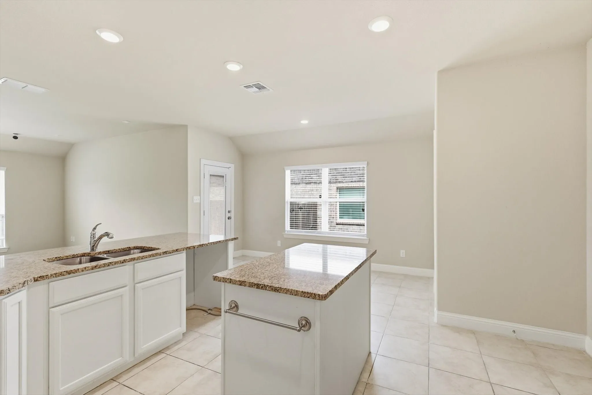 Kitchen featuring white cabinetry, light-toned granite countertops, and a stainless steel sink with a chrome faucet