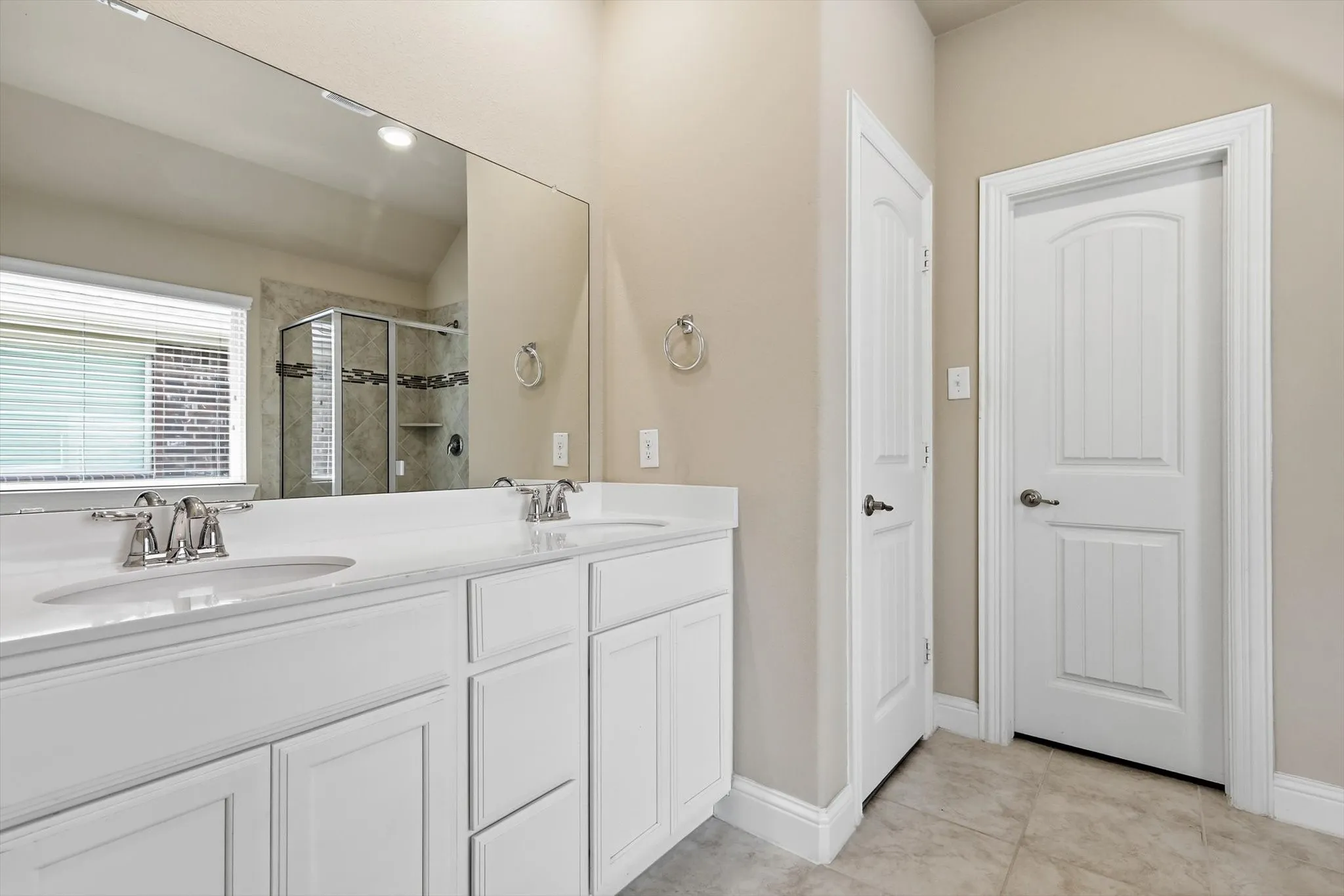 Dual vanity with white cabinetry, undermount sinks, and chrome fixtures