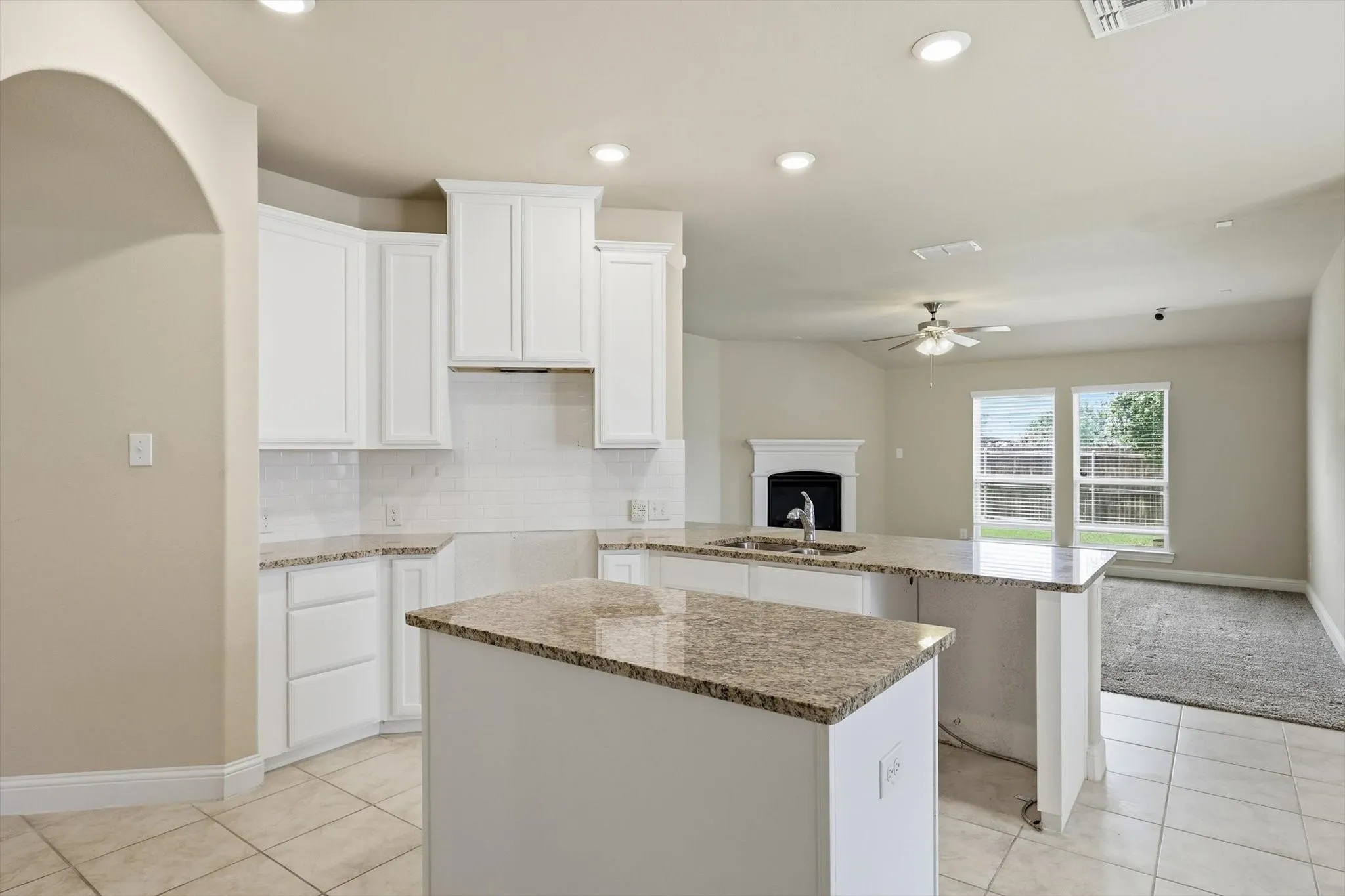 Kitchen featuring white shaker cabinetry, speckled countertops, a subway tile backsplash, and a double island