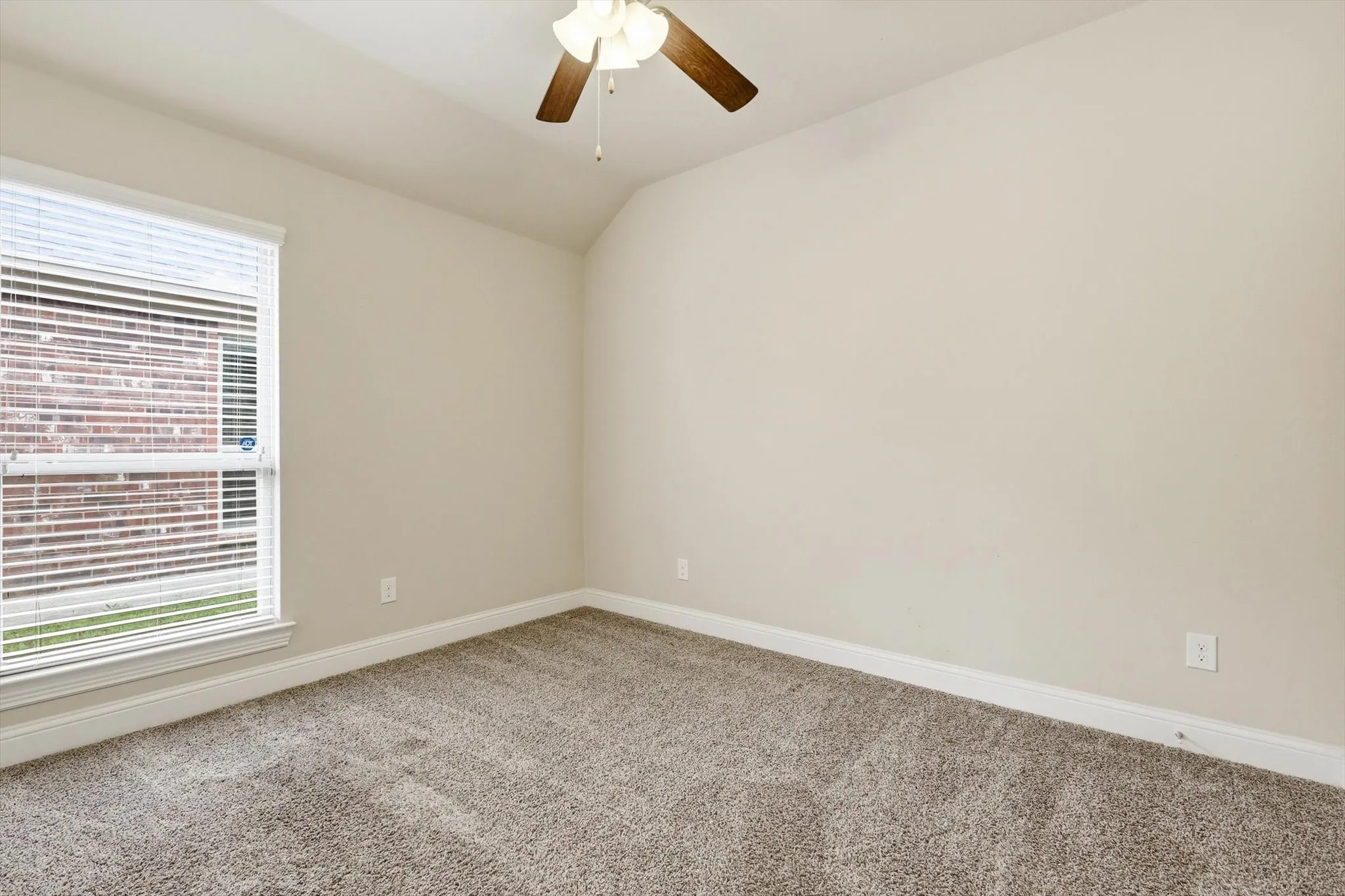 Carpeted room featuring a large window with blinds, a ceiling fan, and light-toned walls