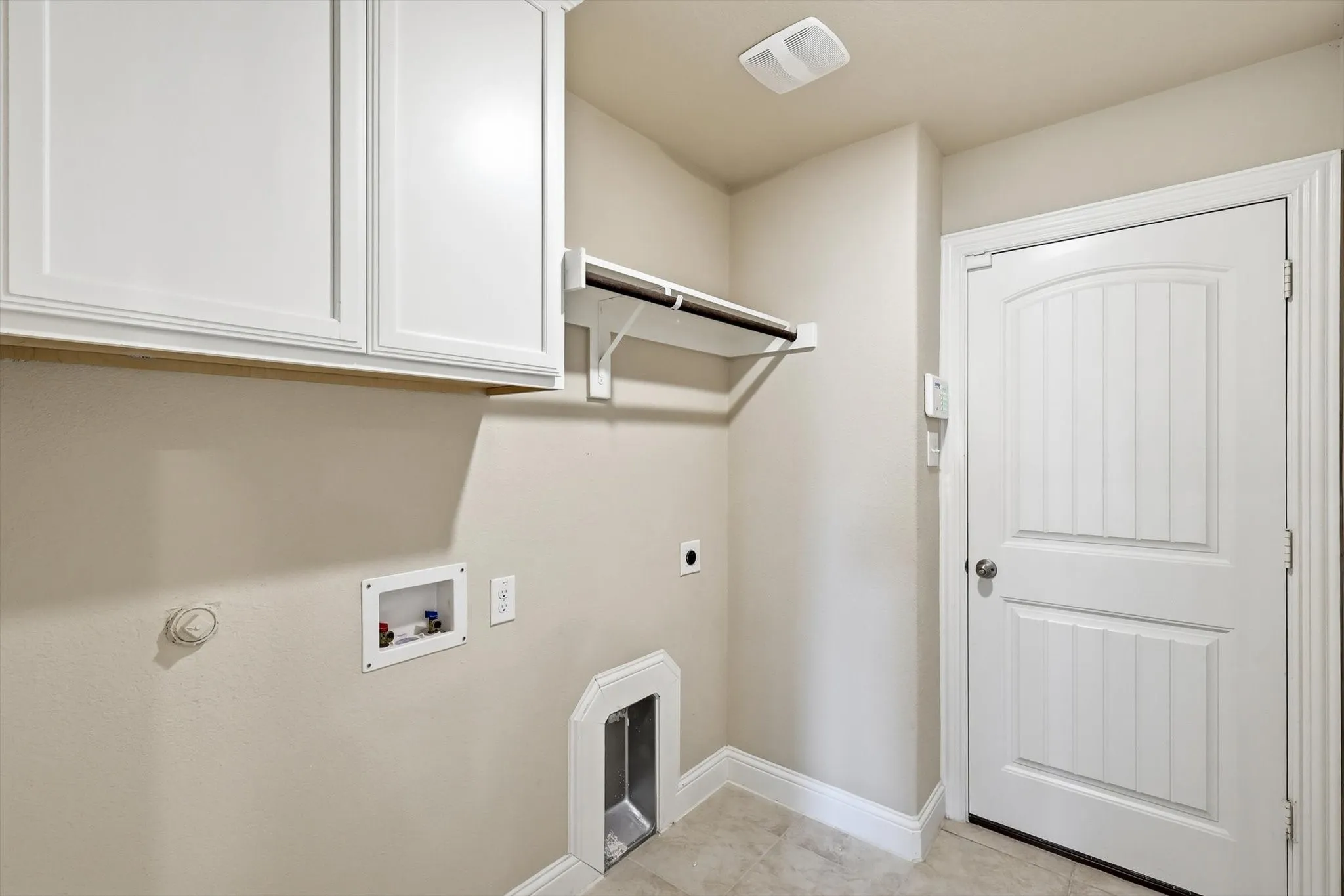 Dedicated utility space featuring light-toned walls and tile flooring