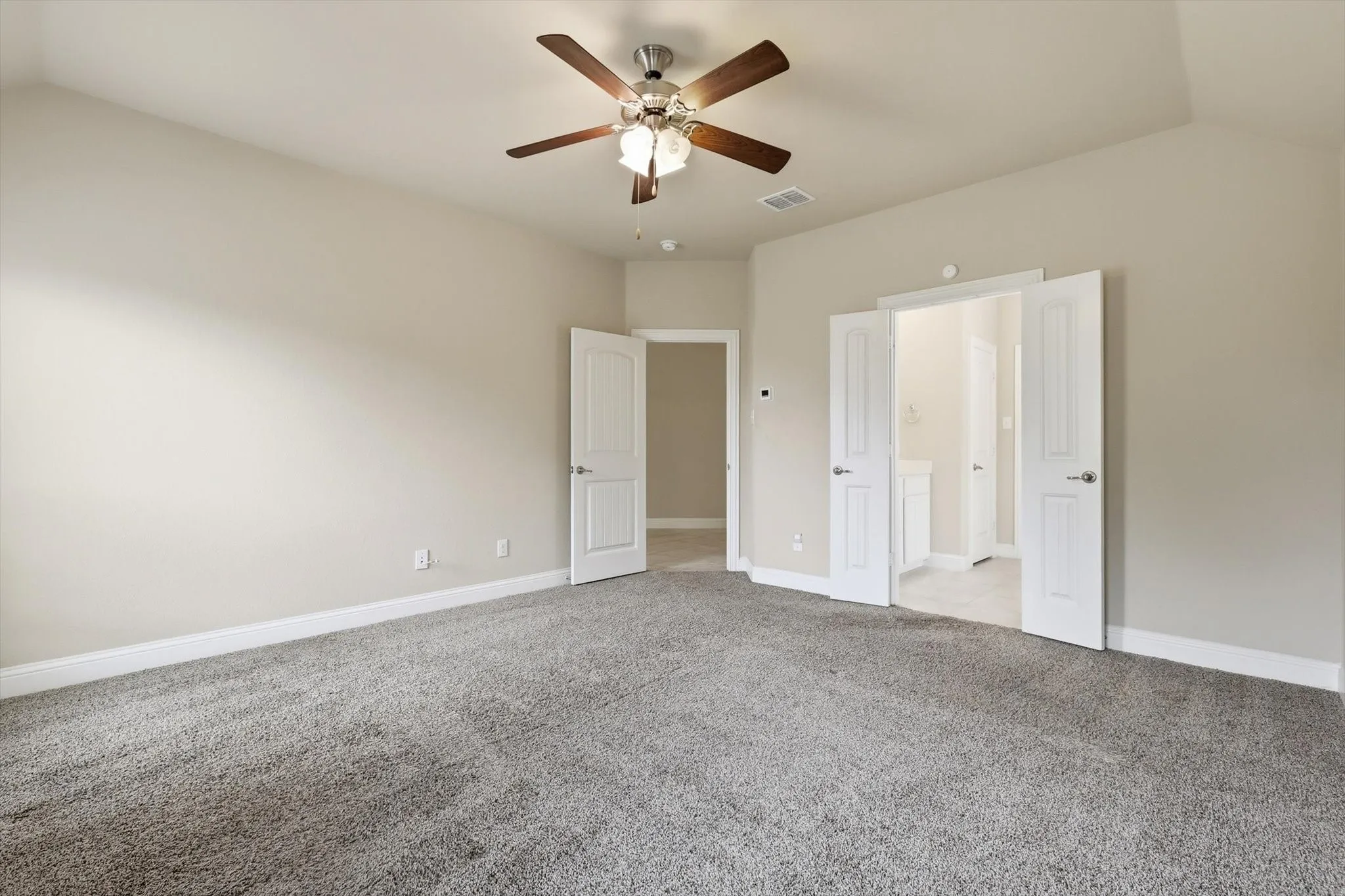 Spacious room featuring vaulted ceilings, neutral-toned walls, and plush carpet flooring