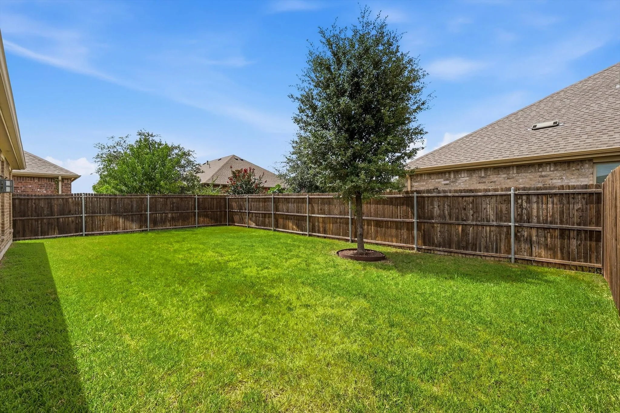 Expansive rear yard featuring green lawn and a perimeter wood privacy fence