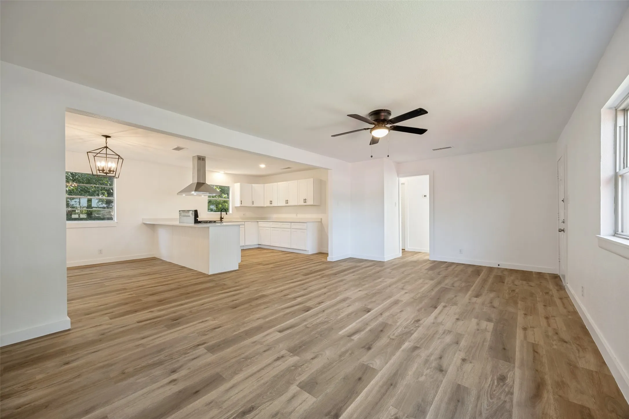 Open-concept living space featuring wood-finish flooring, a modern ceiling fan, and recessed lighting