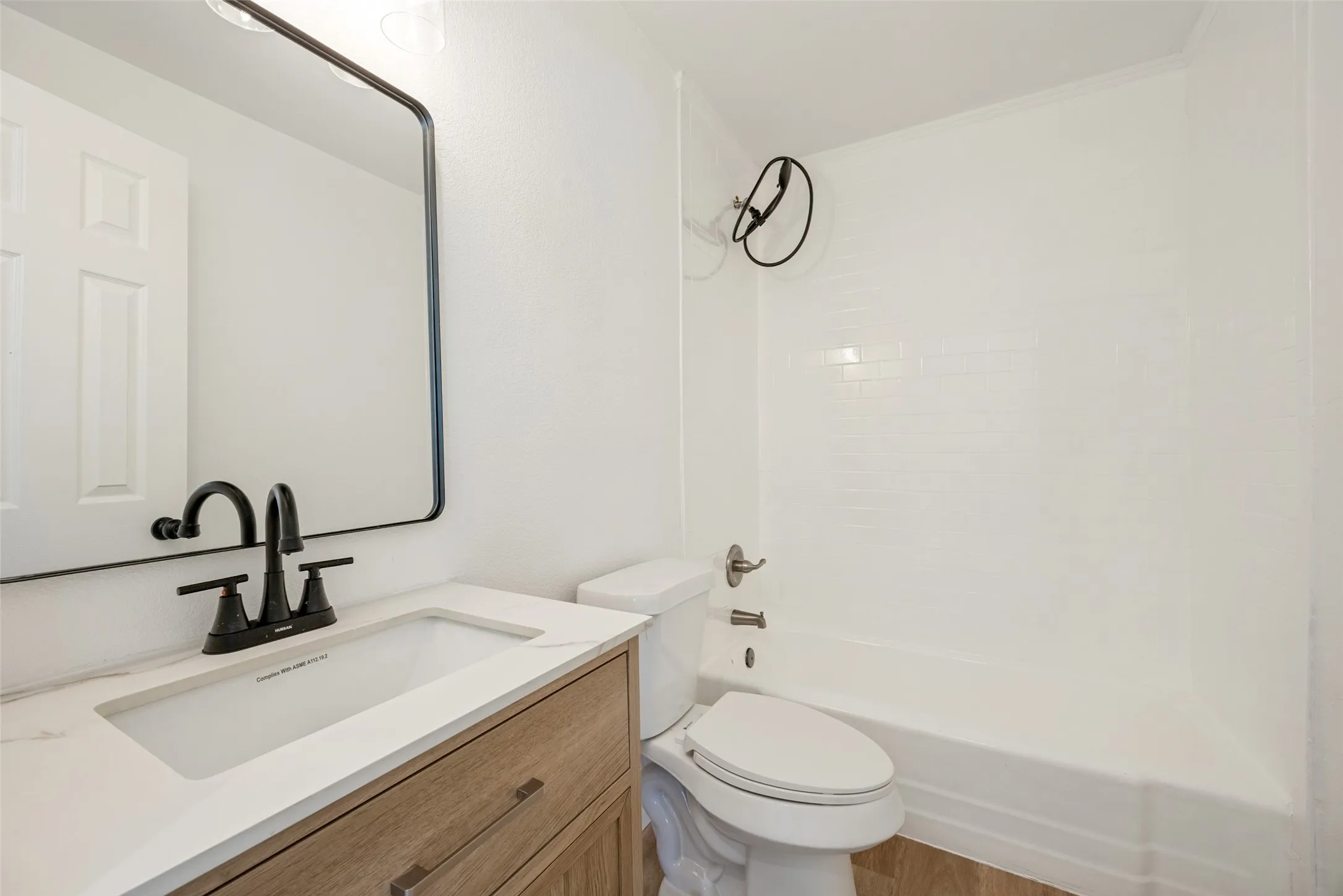 Bathroom featuring a wood-finish vanity with a quartz-look countertop, undermount sink, and matte black faucet