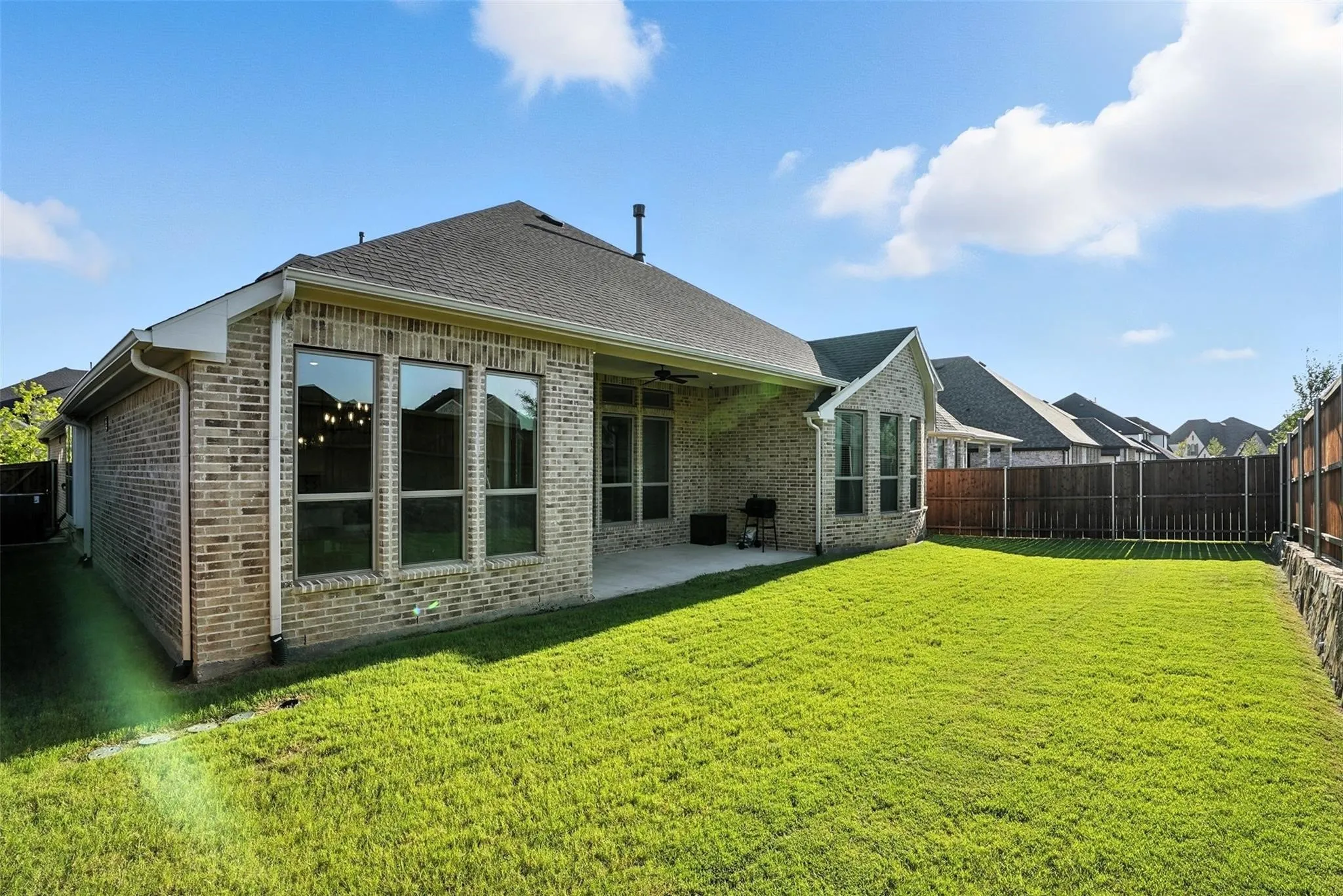Back of house with a fenced backyard, brick siding, a patio area, roof with shingles, and ceiling fan