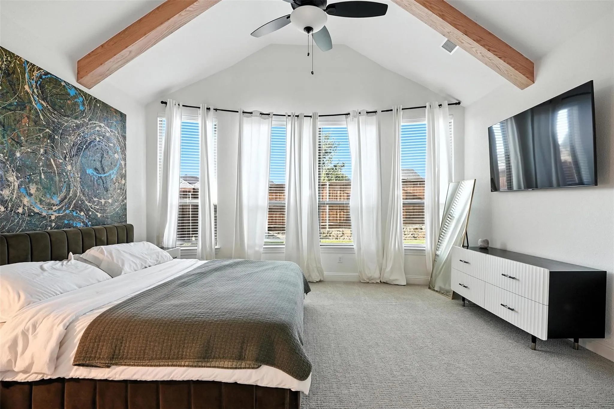 Bedroom featuring light colored carpet, multiple windows, and ceiling fan