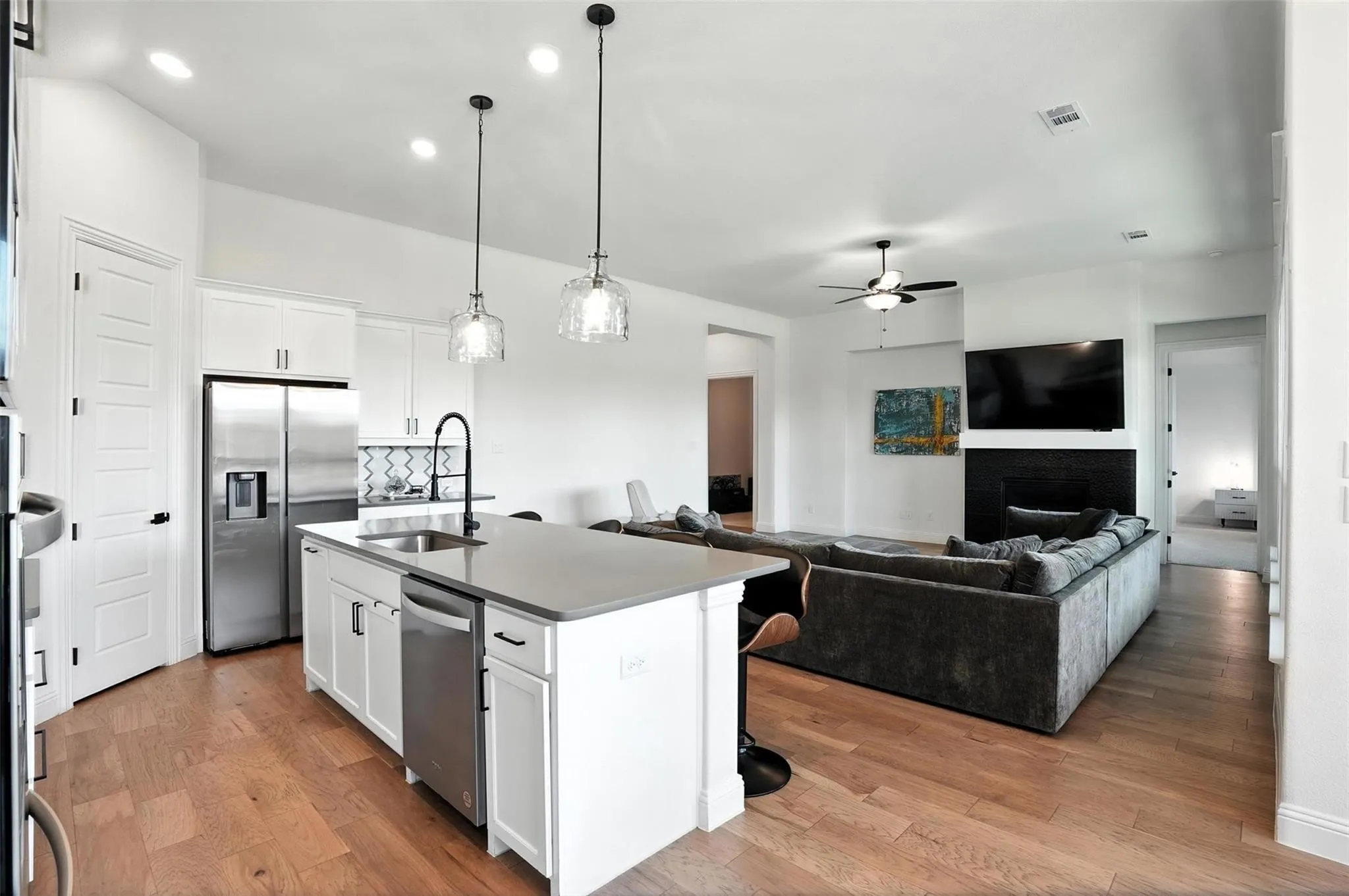 Kitchen with a ceiling fan, appliances with stainless steel finishes, light wood finished floors, an island with sink, and recessed lighting
