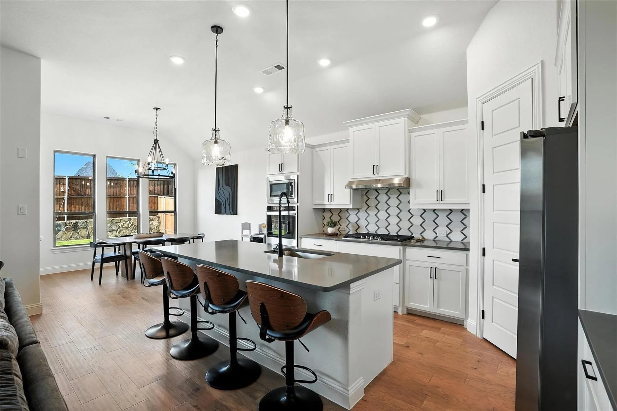 Kitchen featuring dark countertops, decorative backsplash, light wood-style flooring, appliances with stainless steel finishes, and a breakfast bar