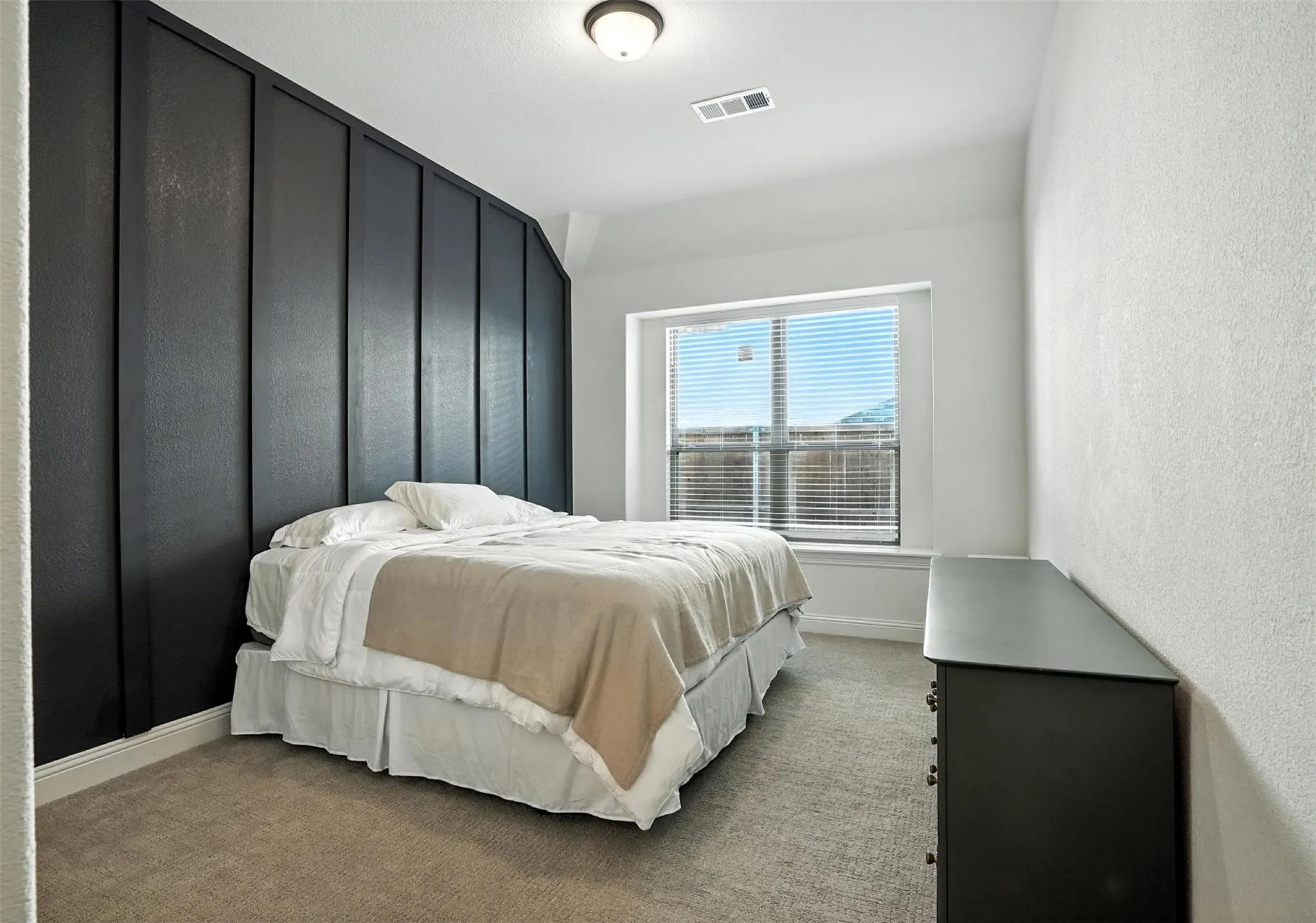 Bedroom featuring light colored carpet and a textured wall