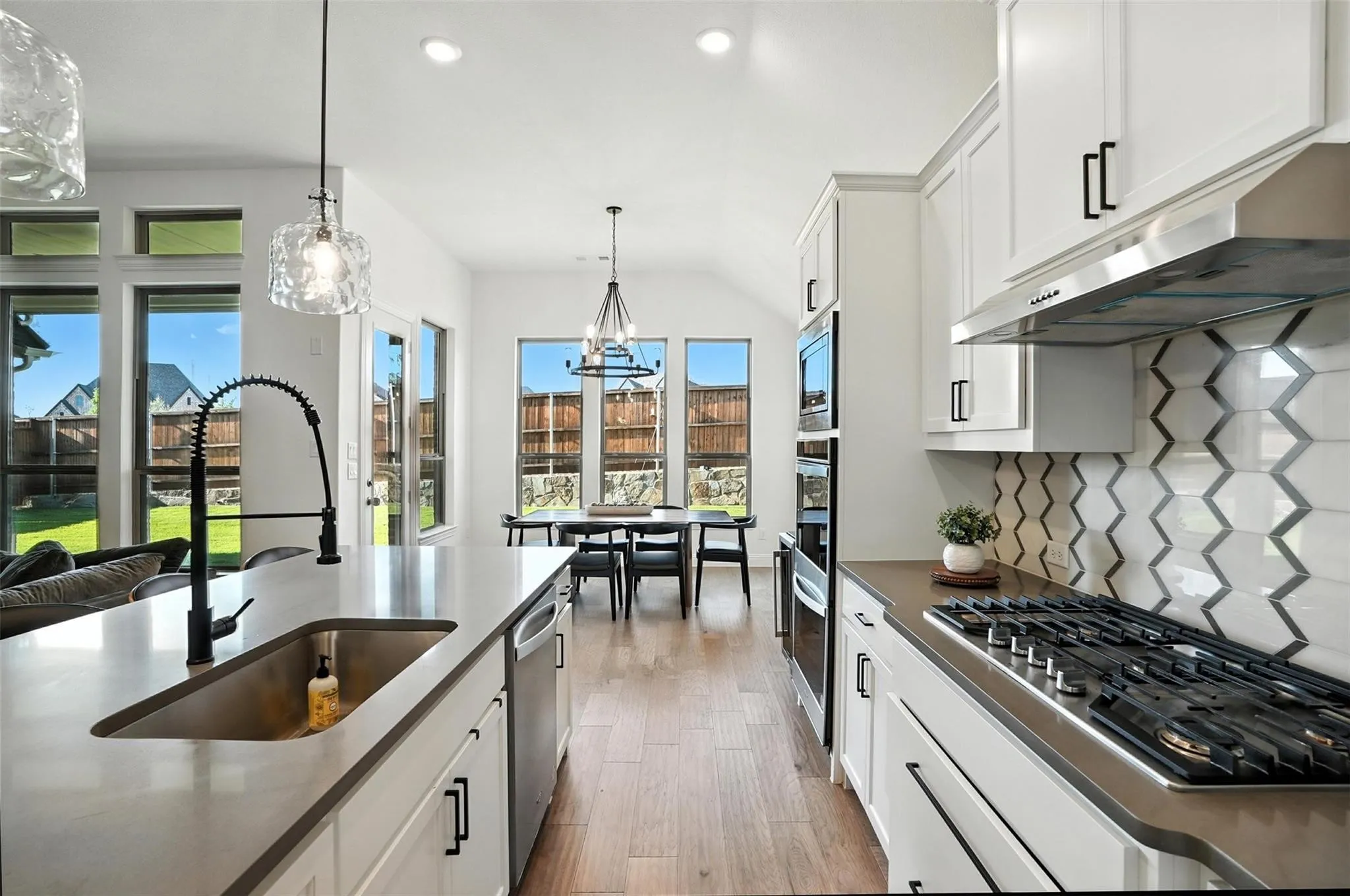 Kitchen with appliances with stainless steel finishes, healthy amount of natural light, exhaust hood, recessed lighting, and white cabinets