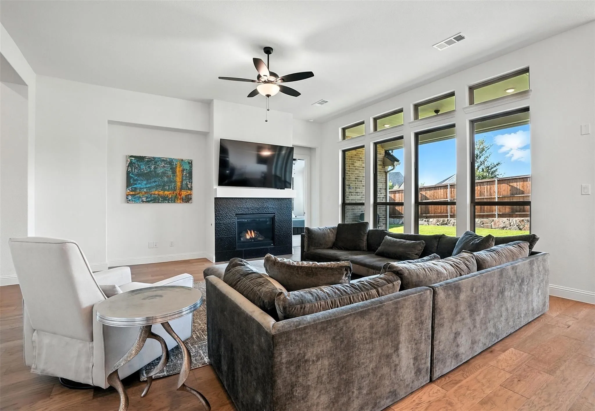 Living room with light wood-type flooring, a tile fireplace, and ceiling fan