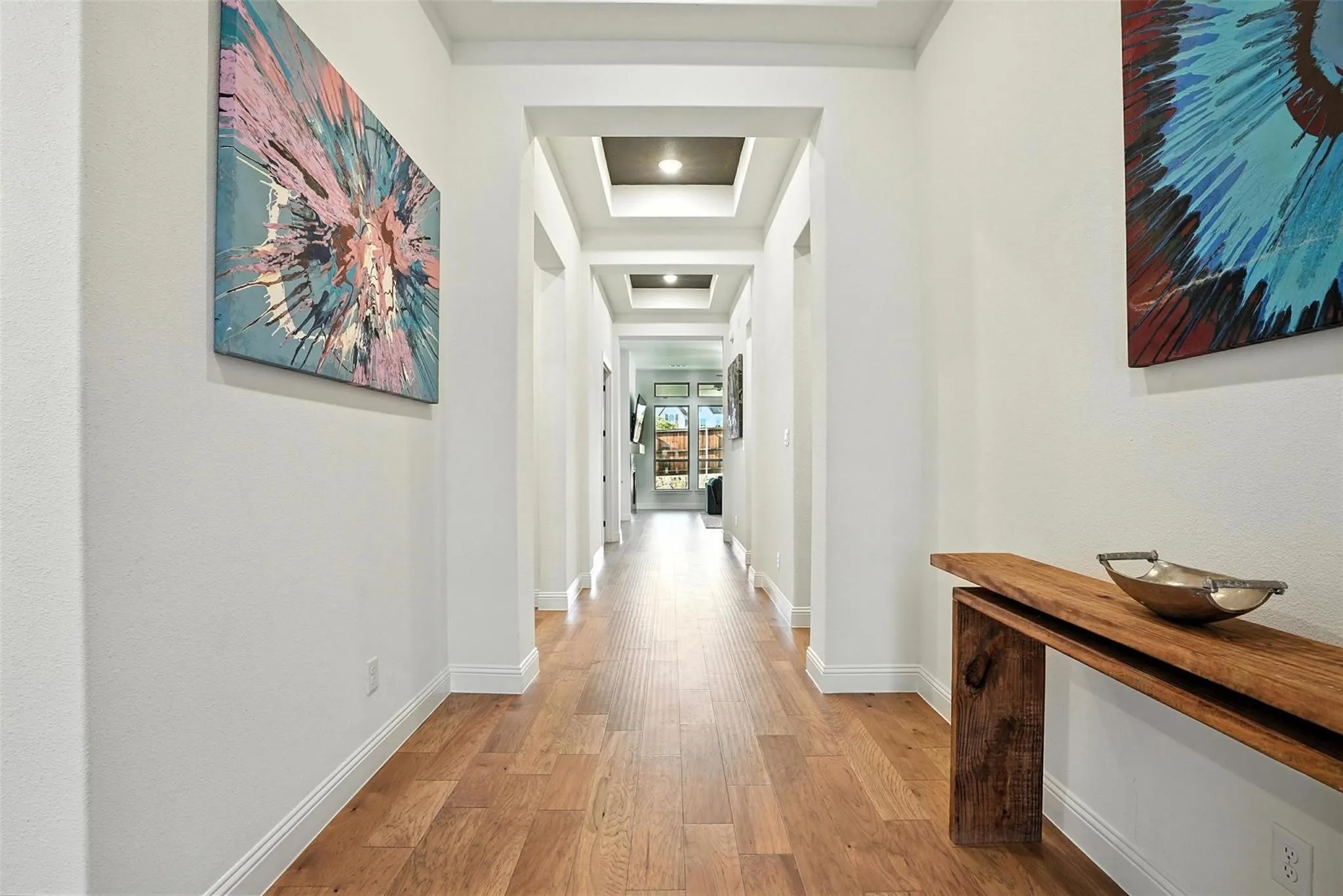 Hall with a tray ceiling and light wood-style flooring