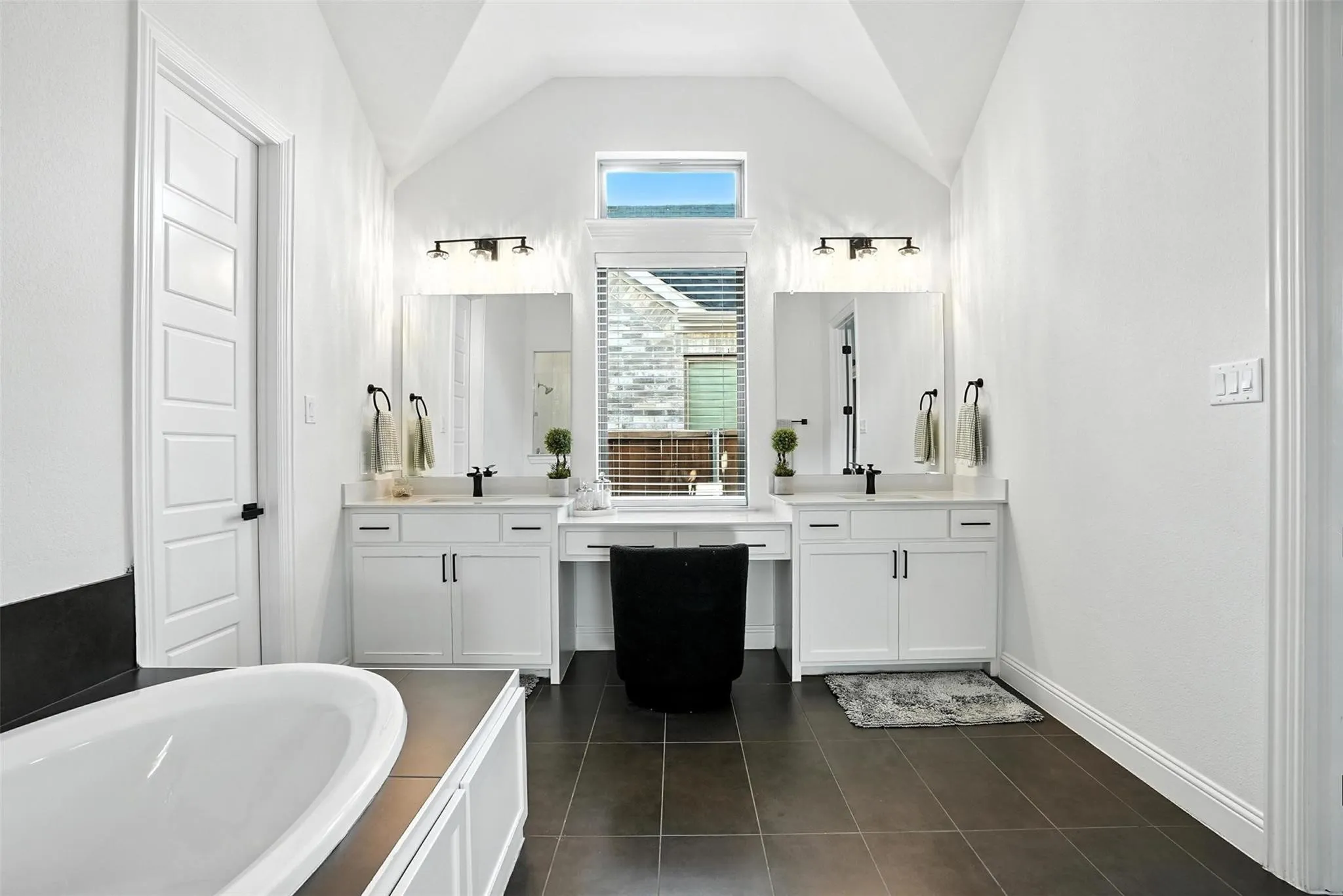 Full bathroom featuring lofted ceiling, vanity, tile patterned flooring, and a tub to relax in