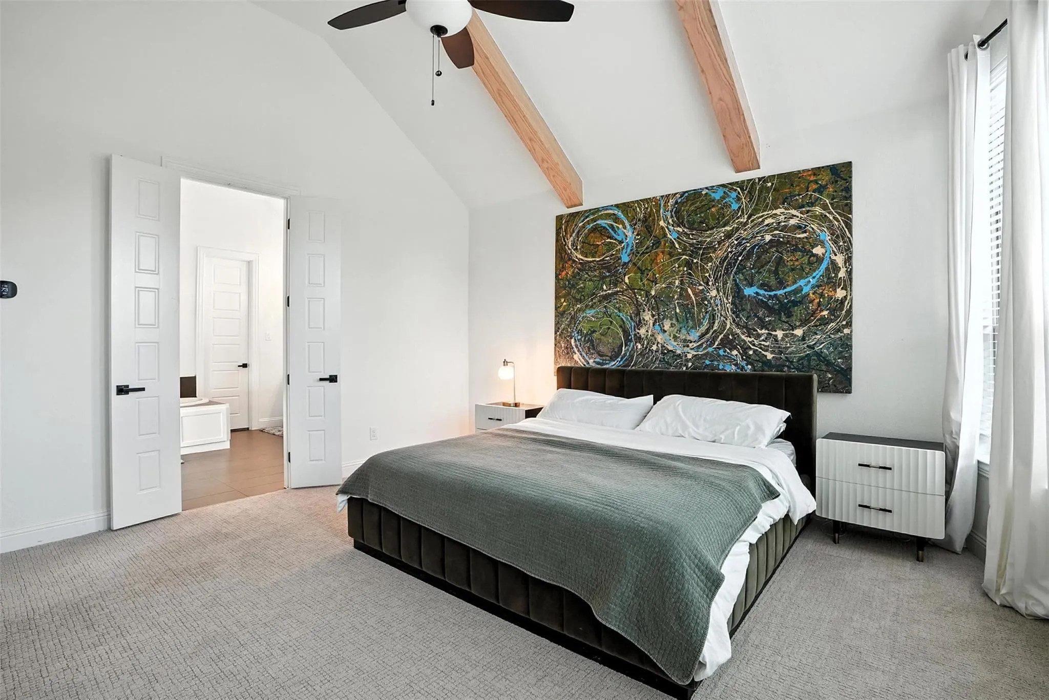 Carpeted bedroom with high vaulted ceiling, beam ceiling, and a ceiling fan