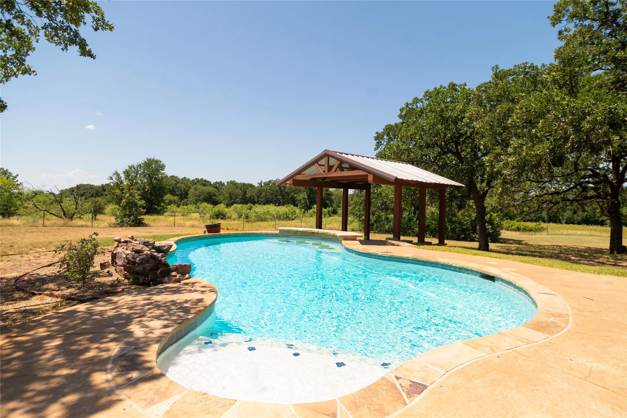 Freeform swimming pool with integrated spa and stone surround