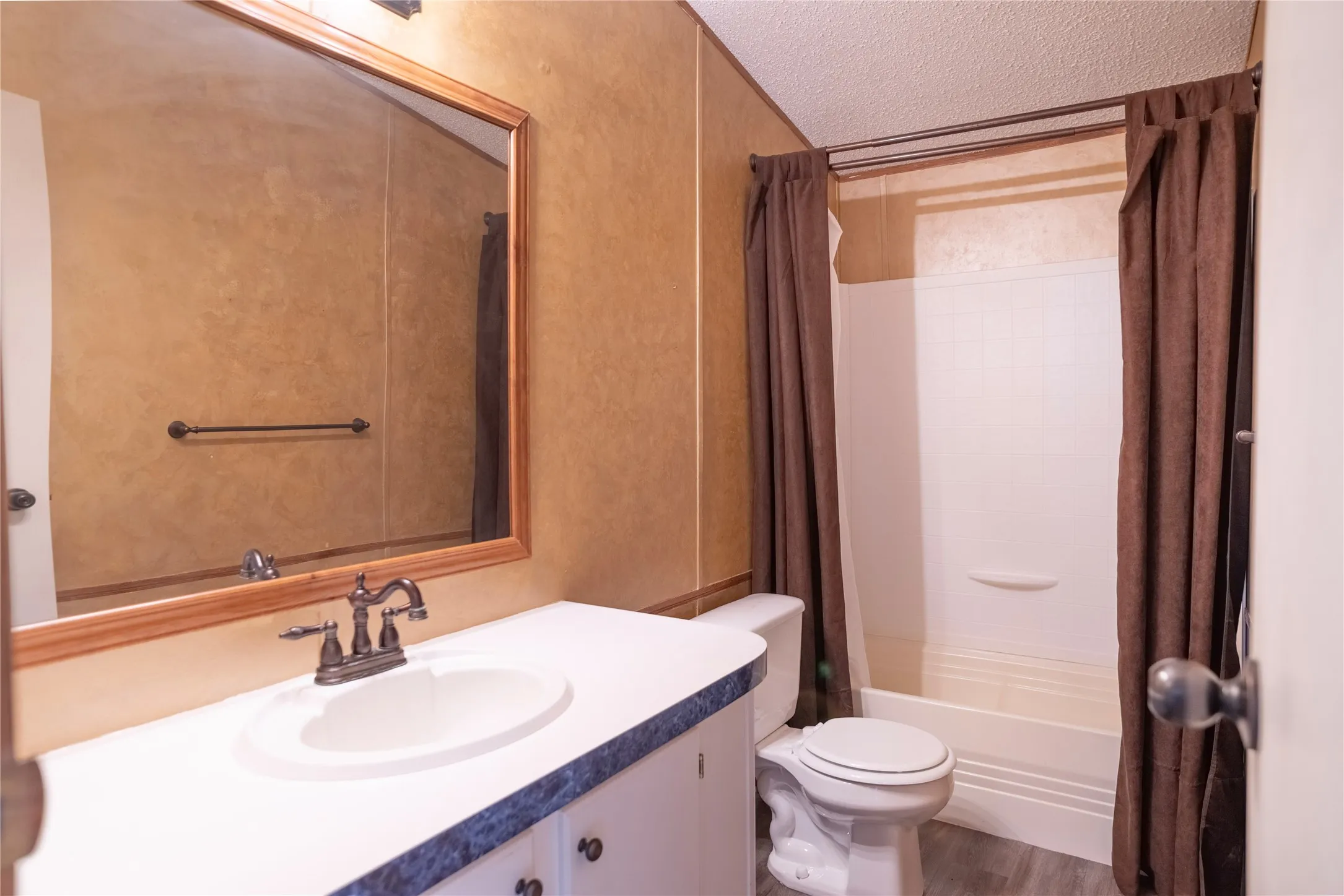 Bathroom featuring a vanity with an integrated sink, a large framed mirror, and a full shower-tub combination