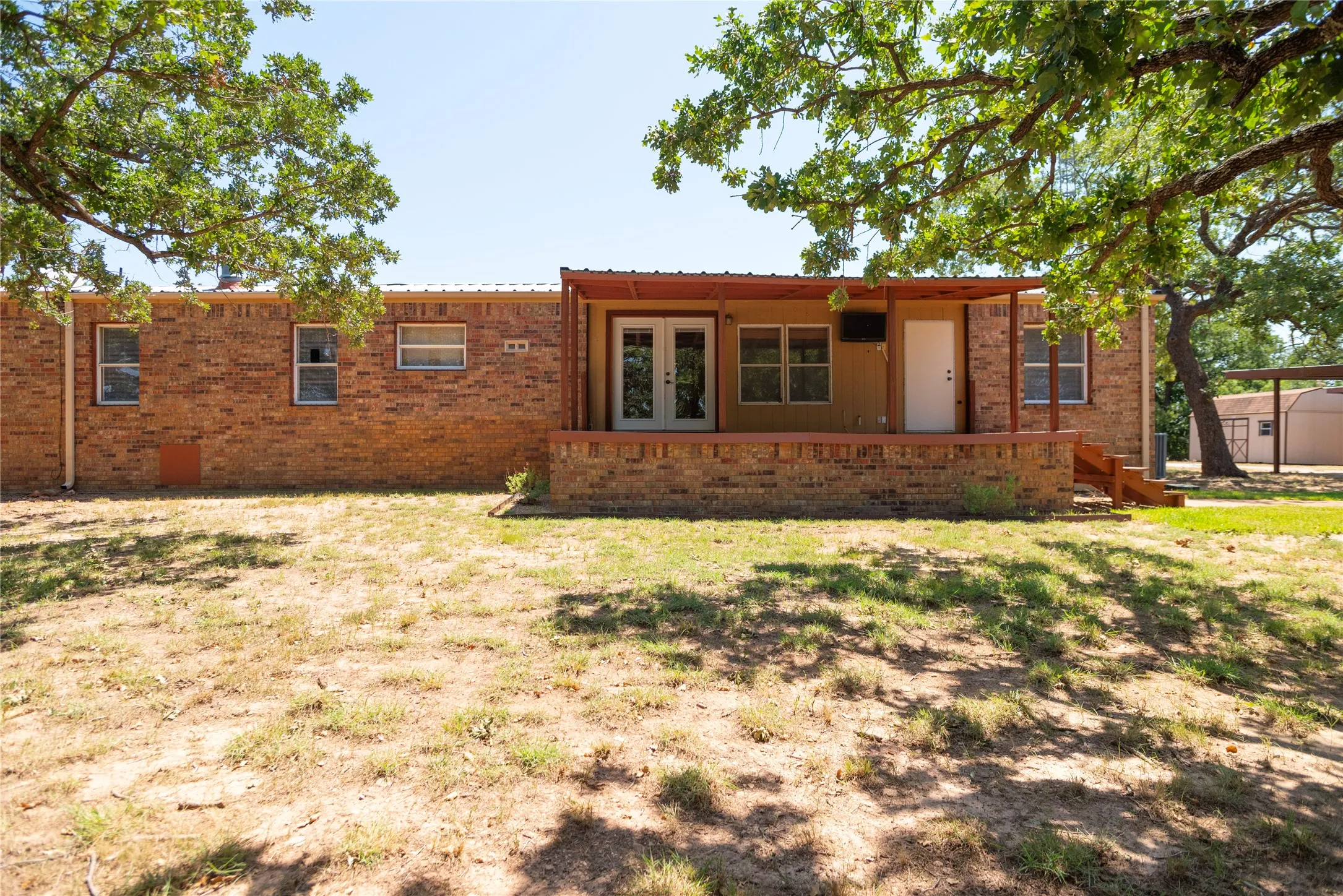 Brick exterior featuring a covered patio with wood-finish supports and steps