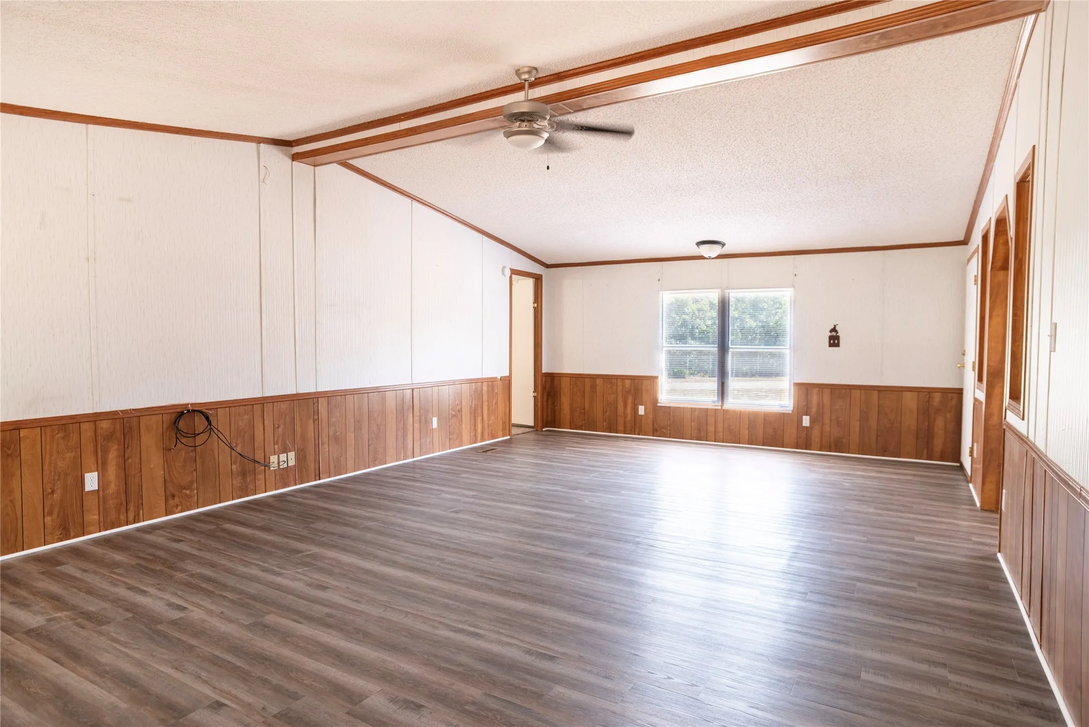 Spacious room featuring wood-finish flooring, white paneling, and wood-paneled wainscoting