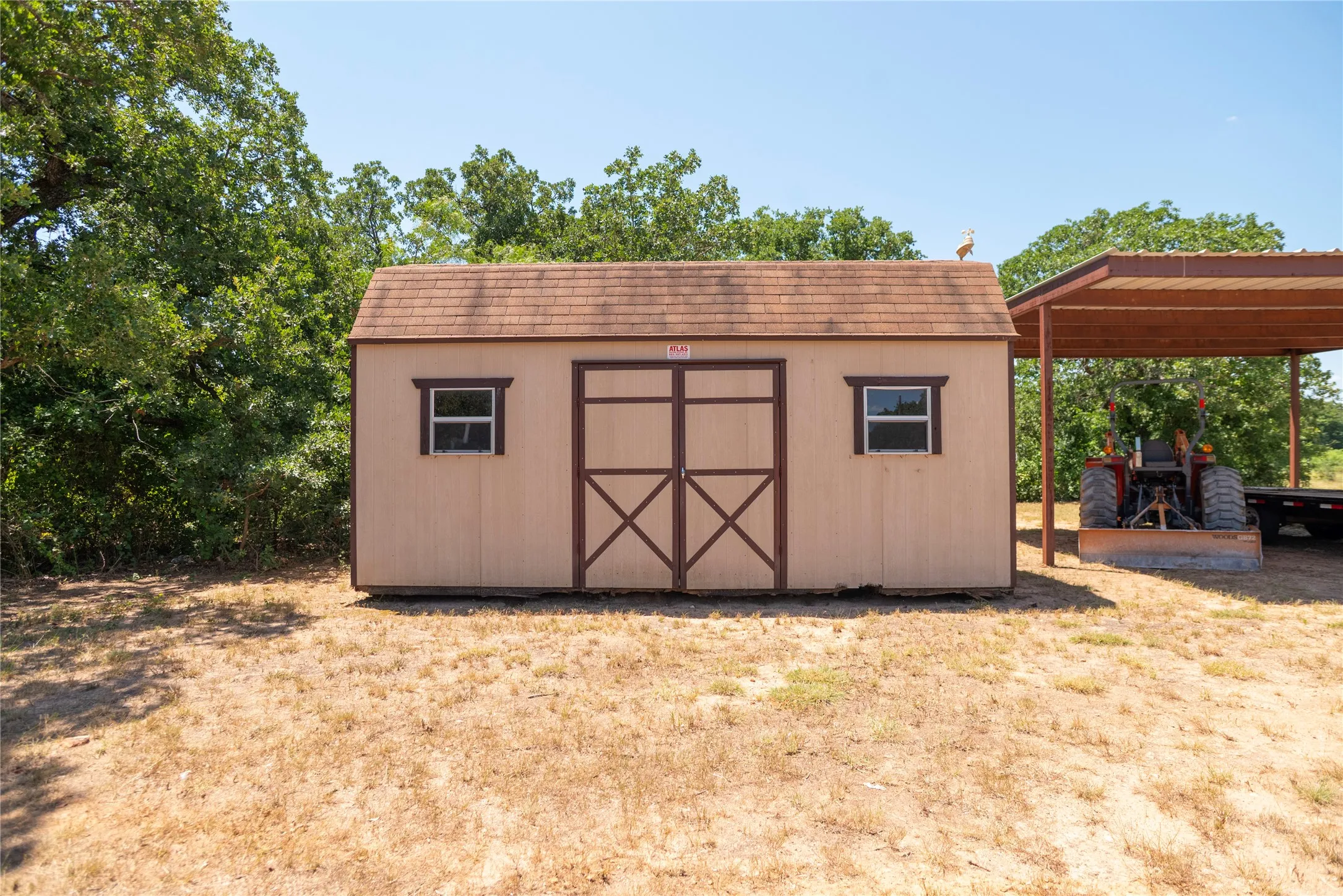 Detached storage shed with dual front doors and two windows, featuring a shingled roof and wood siding