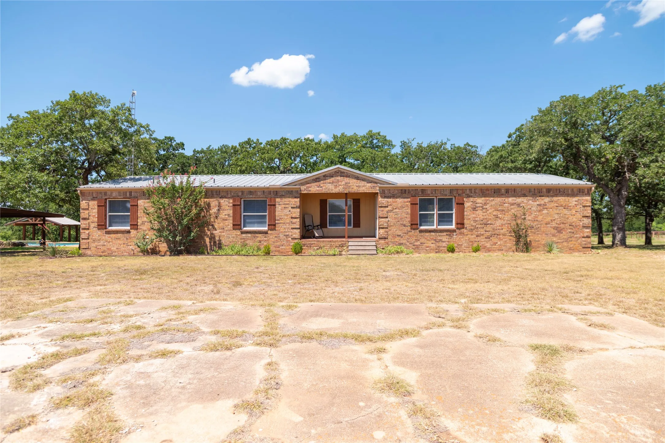 Brick exterior featuring a covered front porch, metal roof, and decorative window shutters
