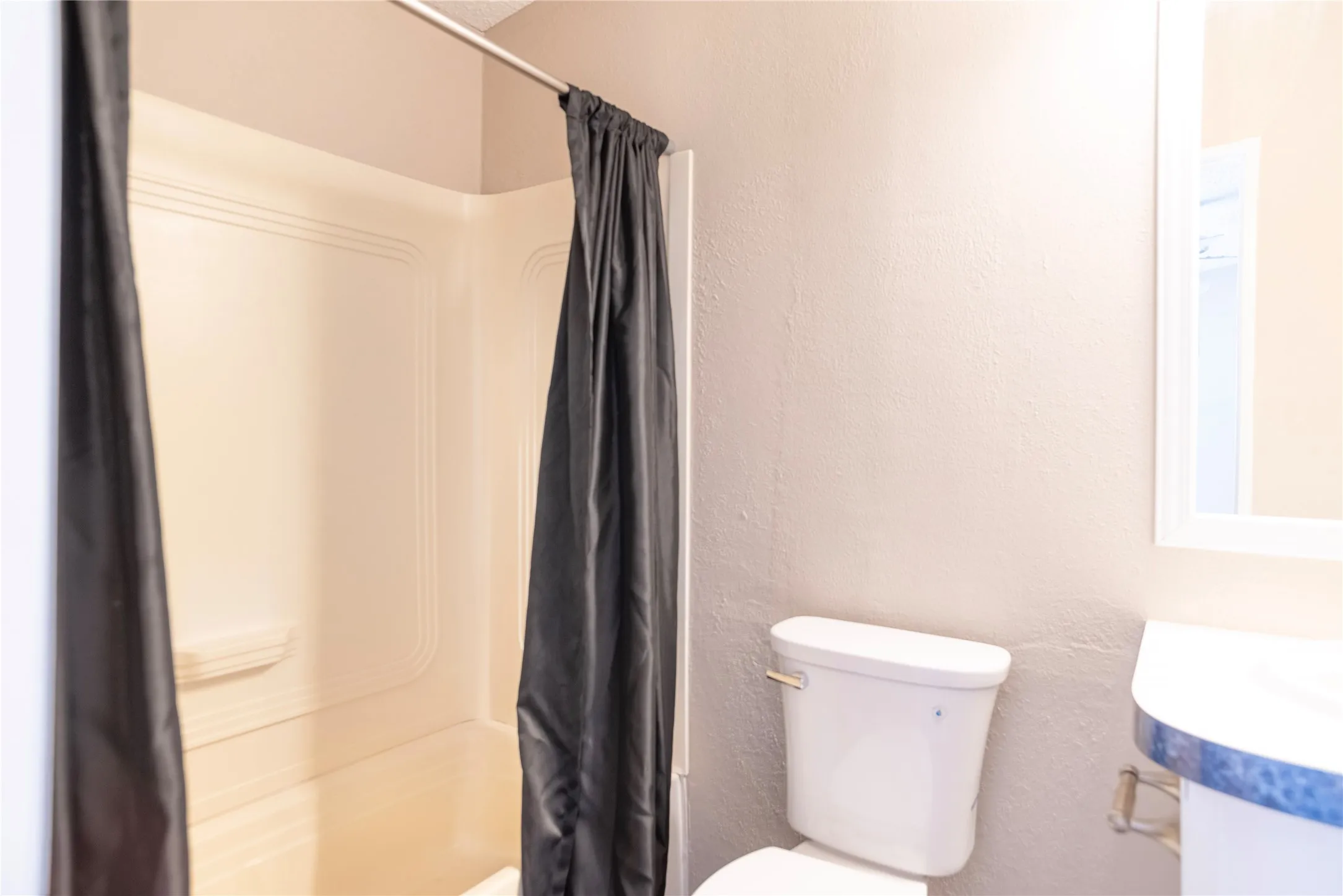 Bathroom featuring a white toilet, a vanity with a countertop, and a shower-tub combination with a white surround