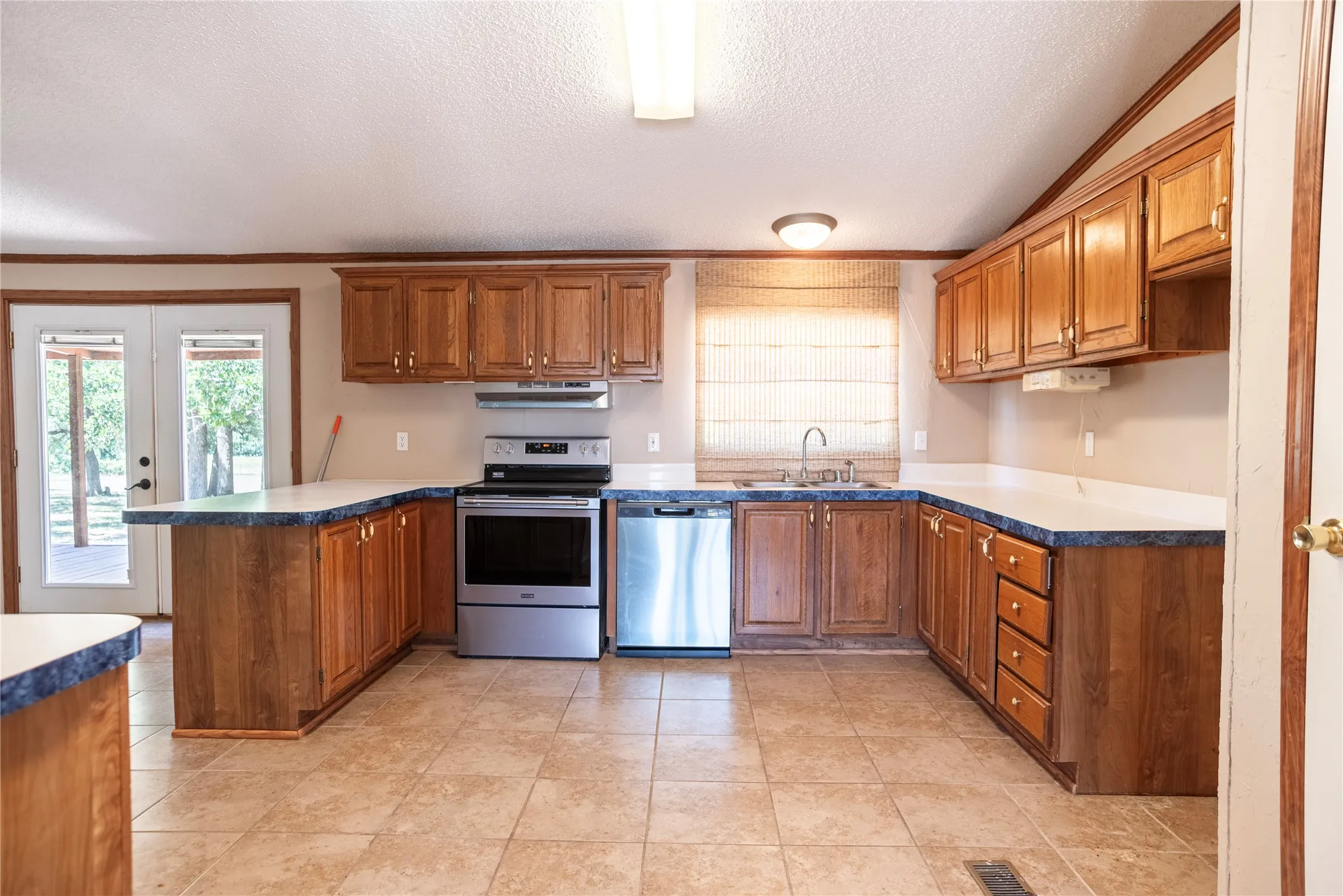 U-shaped kitchen featuring wood cabinetry, stainless steel appliances, and tile flooring