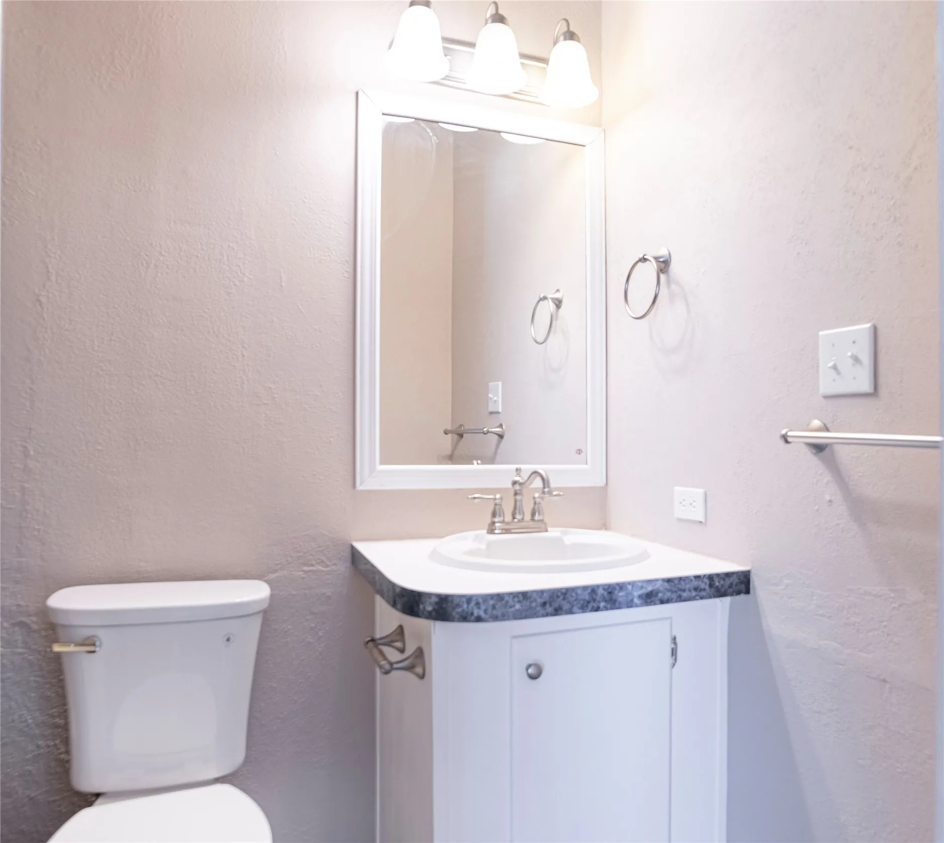 Vanity featuring a white cabinet with a dark patterned countertop and an integrated sink