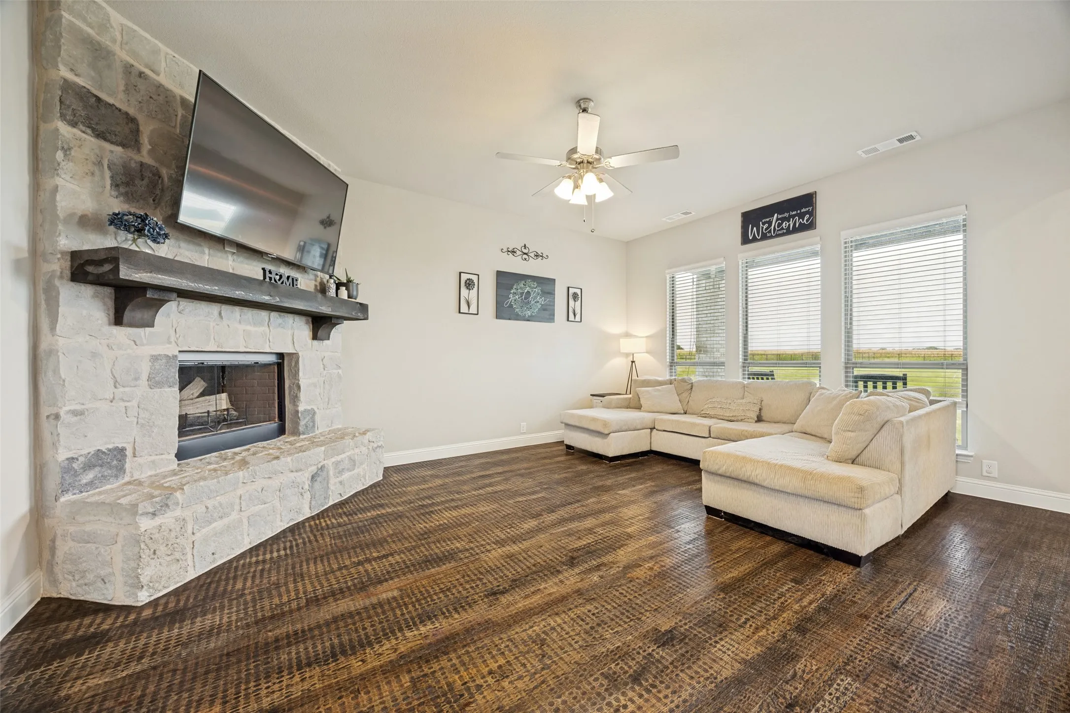 Downstairs Primary primary featuring multiple windows with blinds, light-toned carpeting, a ceiling fan with integrated lighting, and neutral wall tones