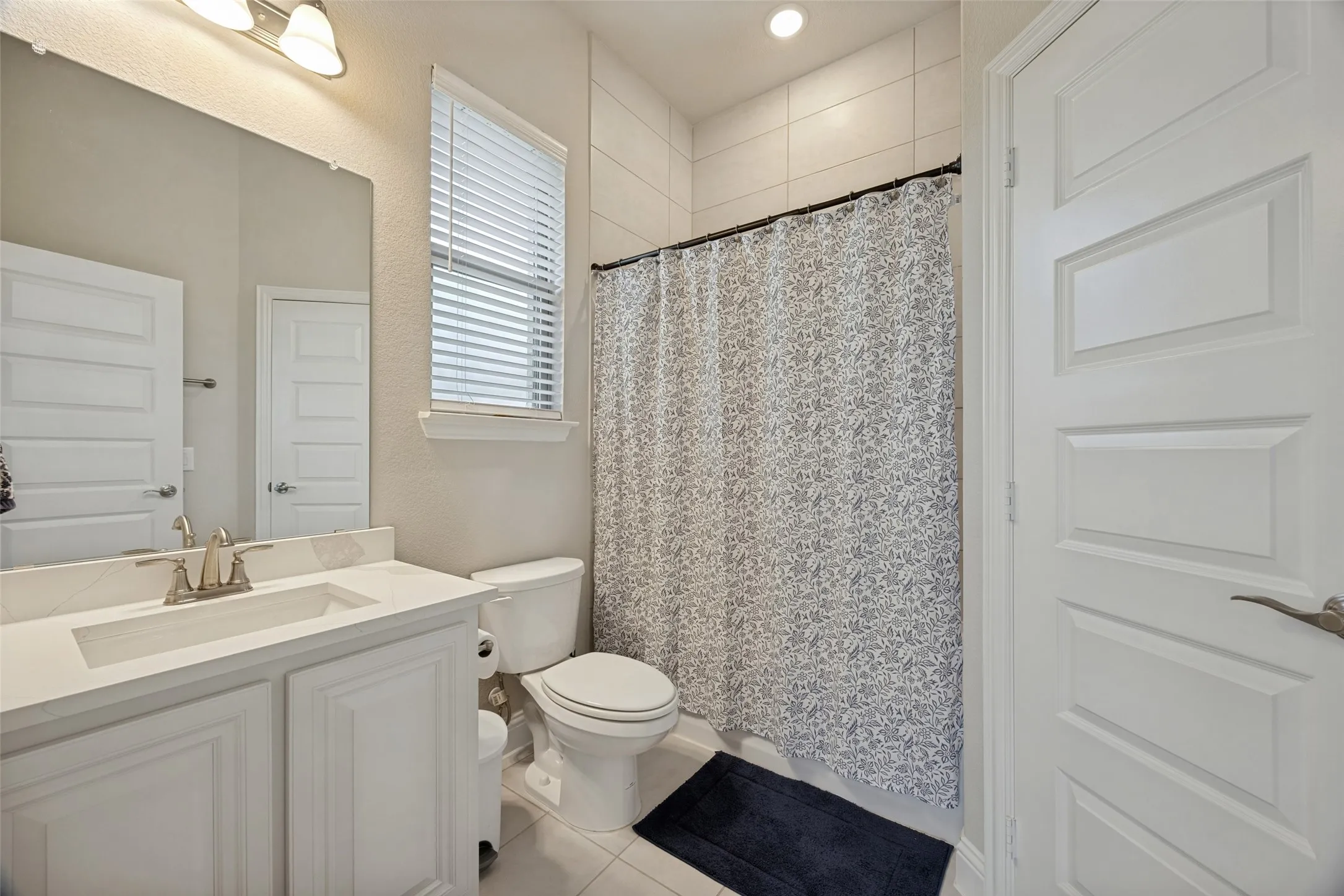 Ensuite bathroom featuring a single vanity with an integrated sink, brushed nickel faucet, and a large mirror