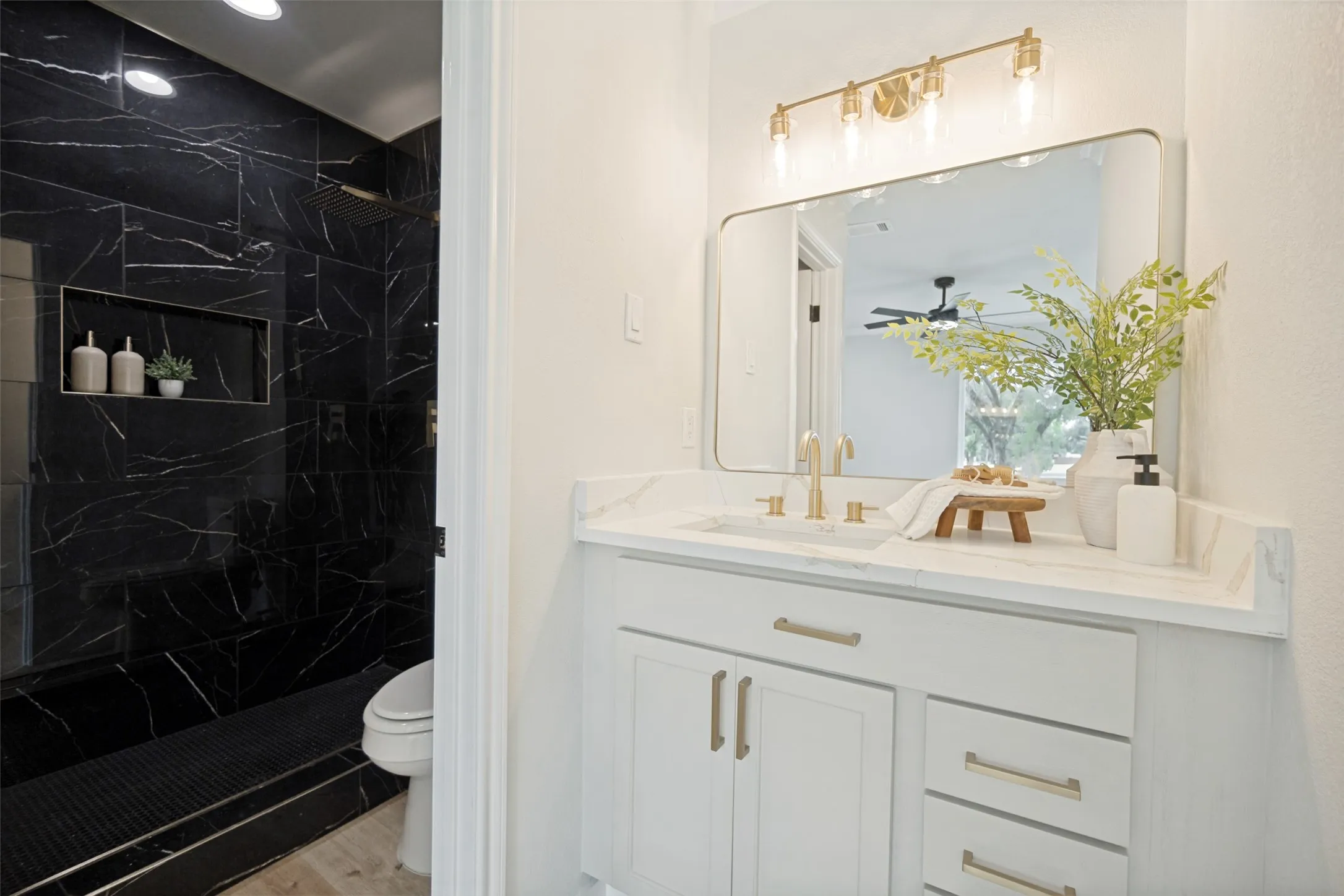 White vanity with gold-tone hardware, rectangular mirror, and a gold-tone light fixture