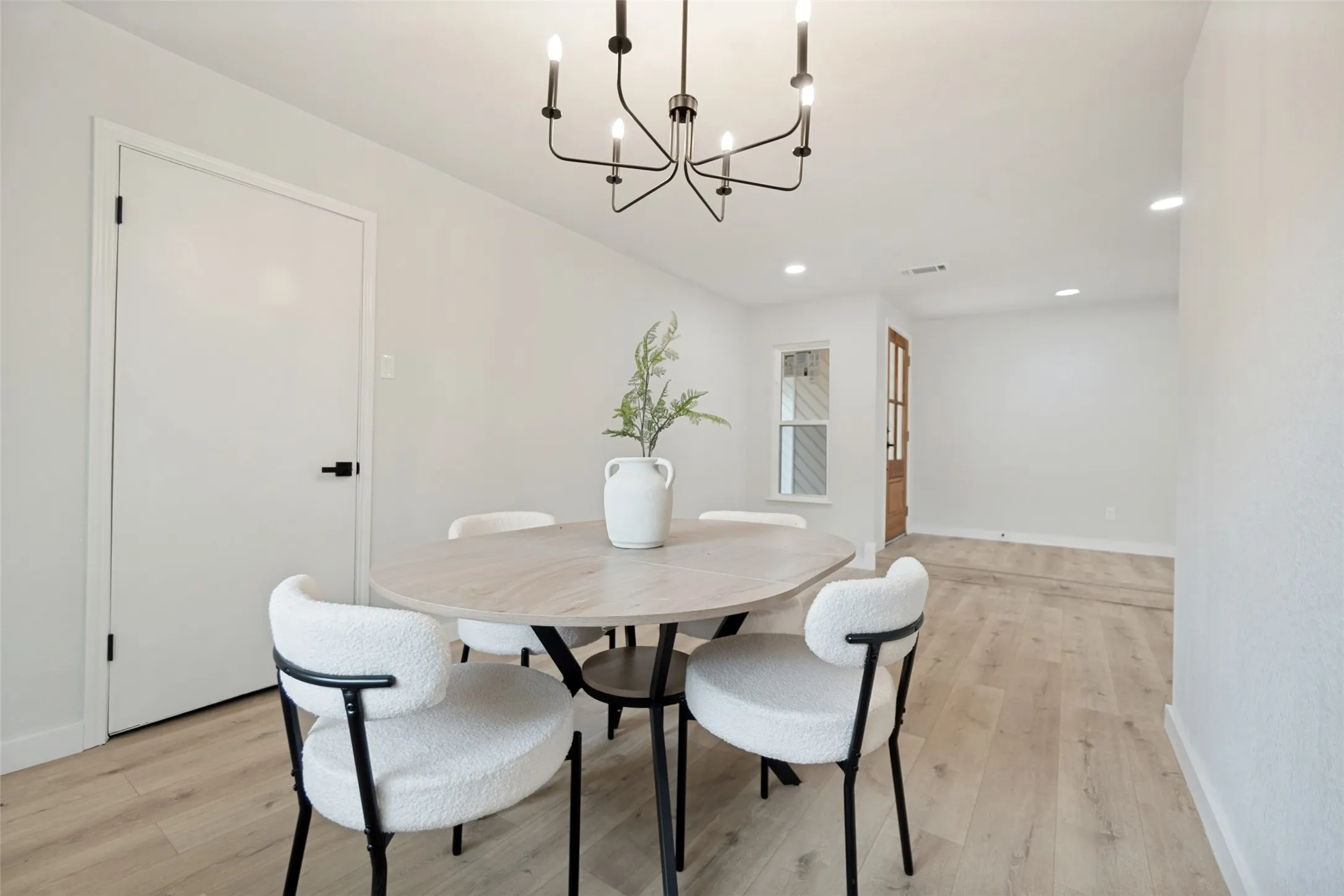 Bright interior space with light wood-finish flooring, recessed lighting, and a modern black chandelier