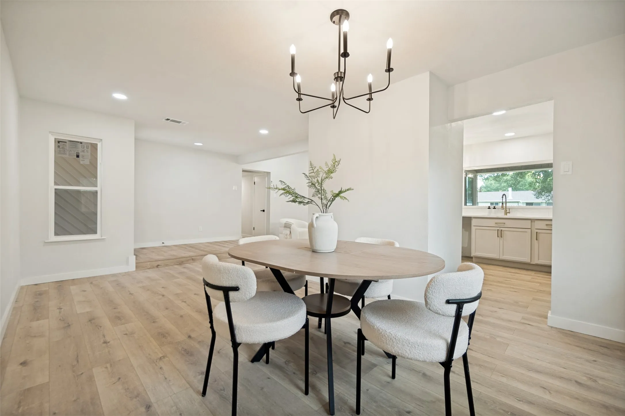 Dining area featuring light wood-finish flooring, a contemporary chandelier, and recessed lighting
