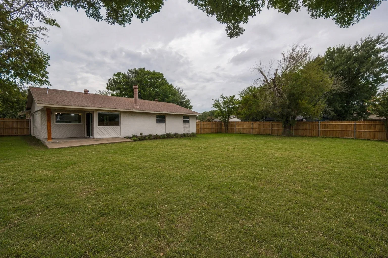 Expansive grassy lawn with a wood privacy fence