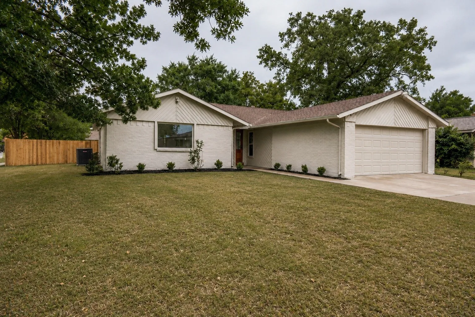 Single-story residence featuring a two-car garage, brick exterior, and a new privacy fence