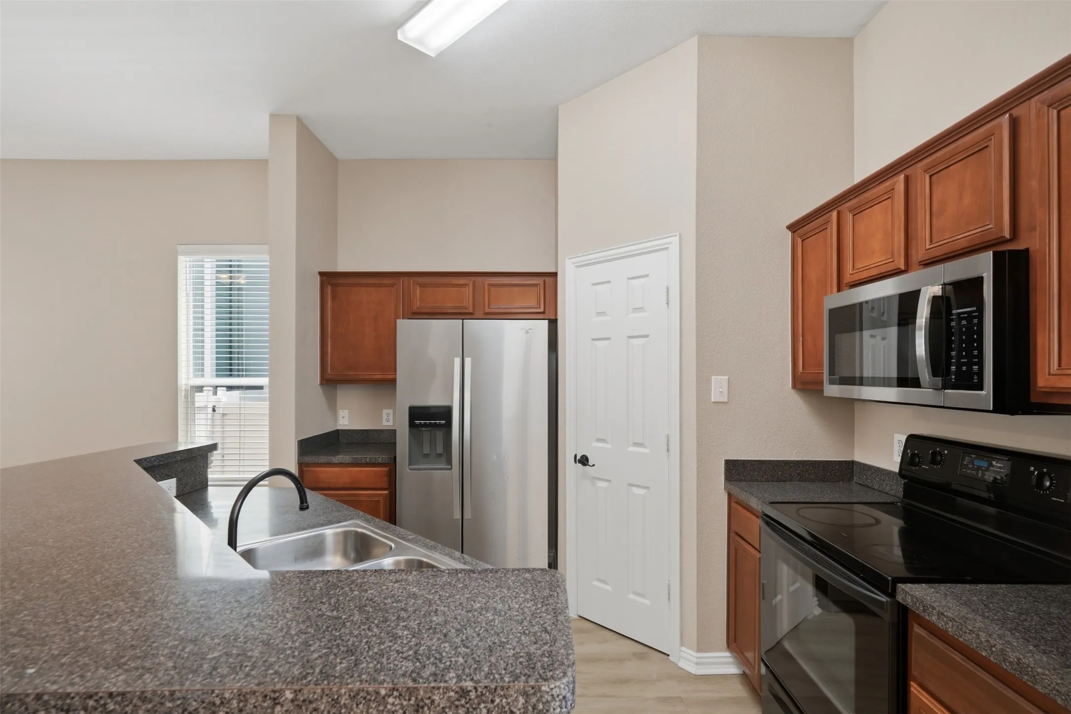 Rich wood cabinetry paired with ample countertop space provides excellent storage and functionality for meal preparation.