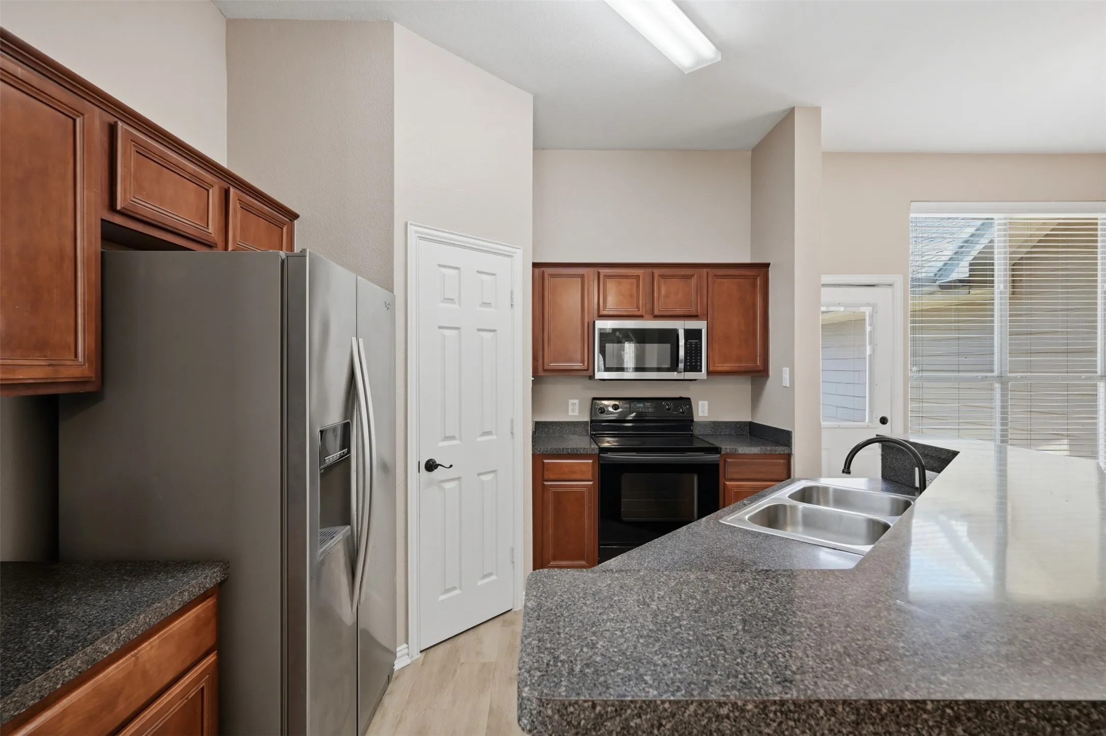 Kitchen features stainless steel refrigerator, built-in microwave, and a smooth-top electric range for a modern touch.