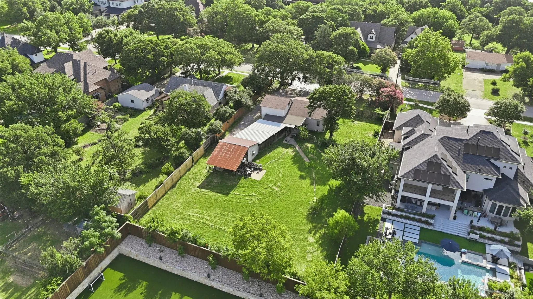 Expansive property featuring a large green lawn, mature trees, and a privacy fence