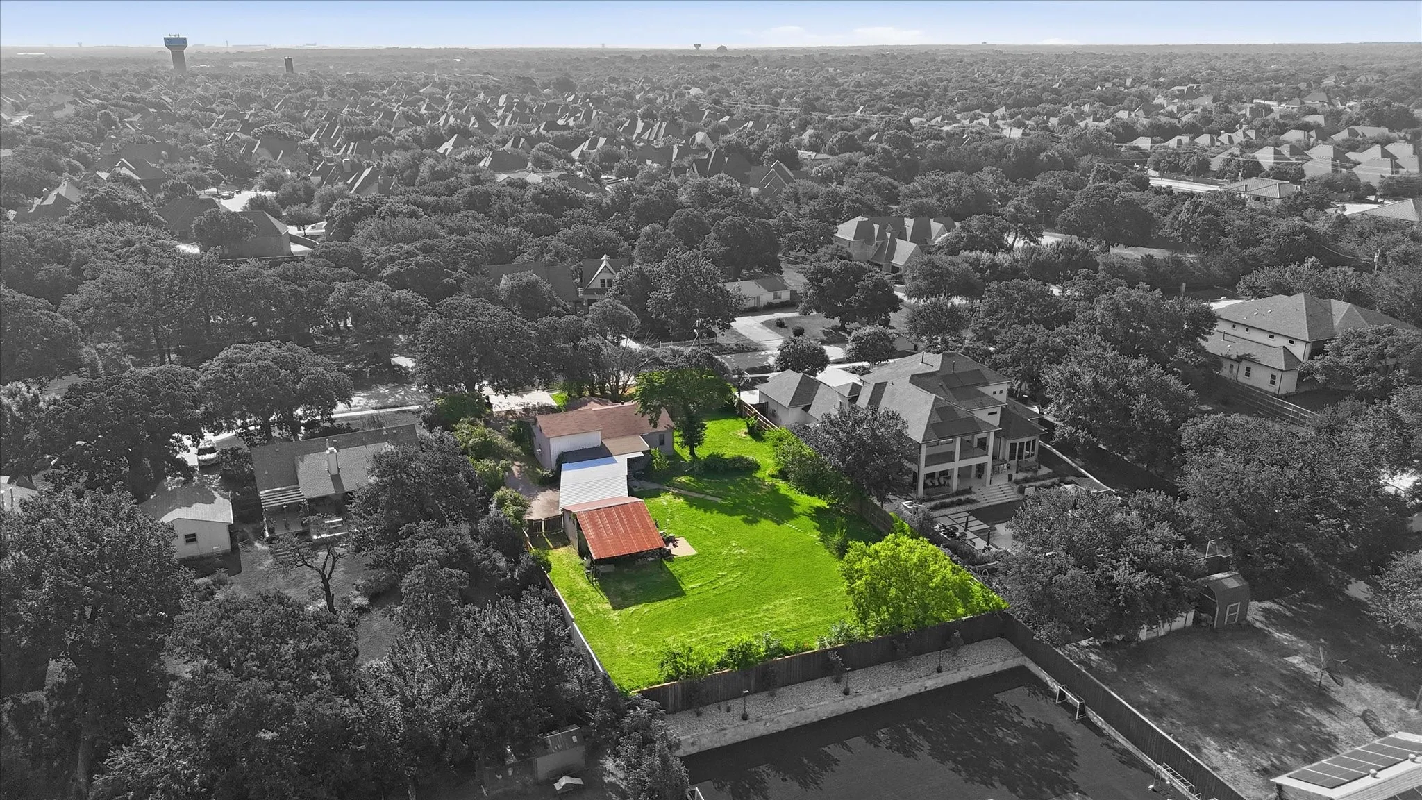 Expansive green lawn with mature trees and perimeter fencing